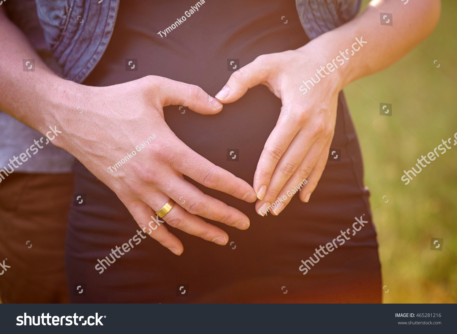 Pregnant Belly with fingers of husband Heart symbol #465281216