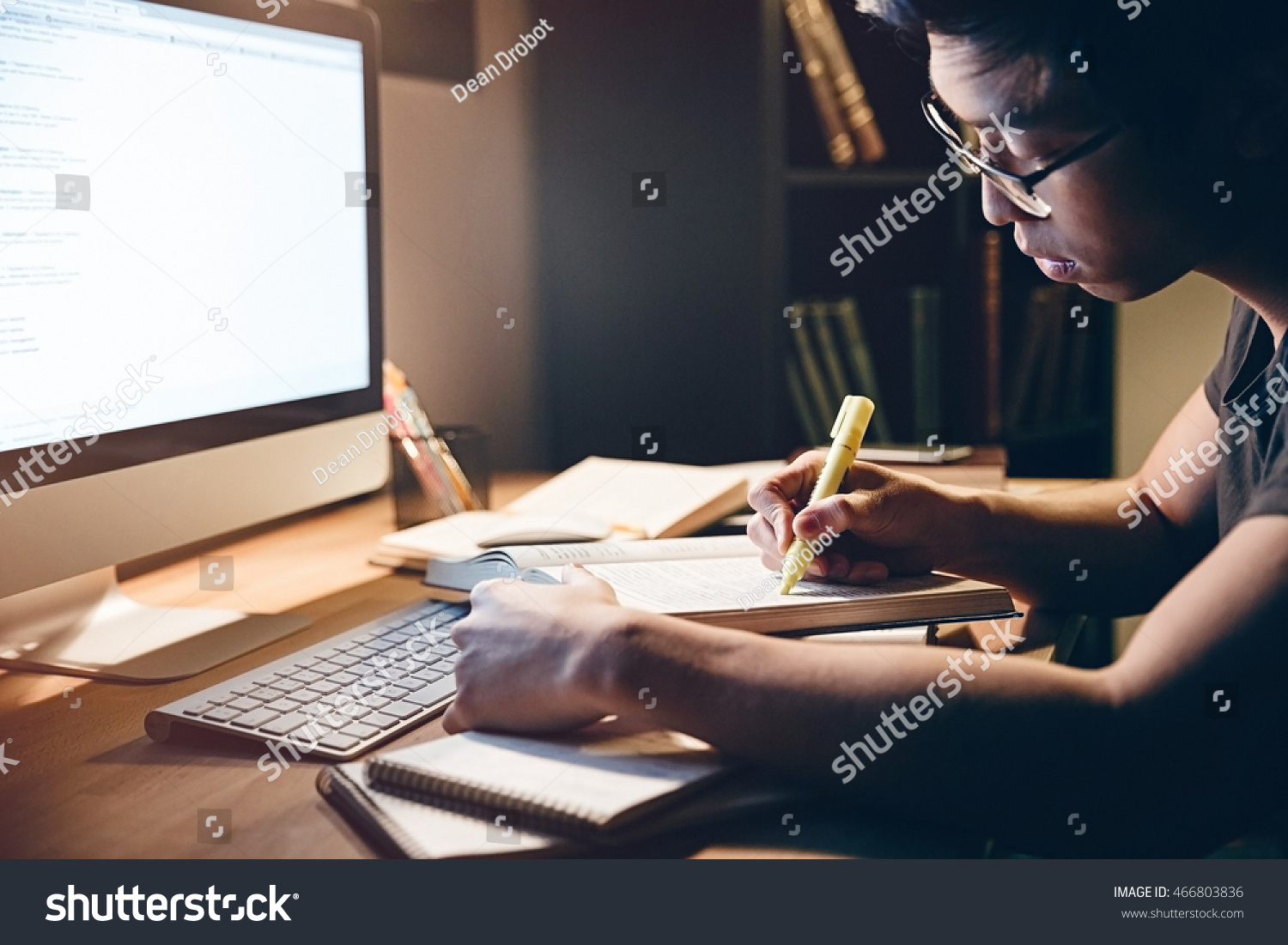 Serious asian young man studying with books and computer in dark room at home  #466803836