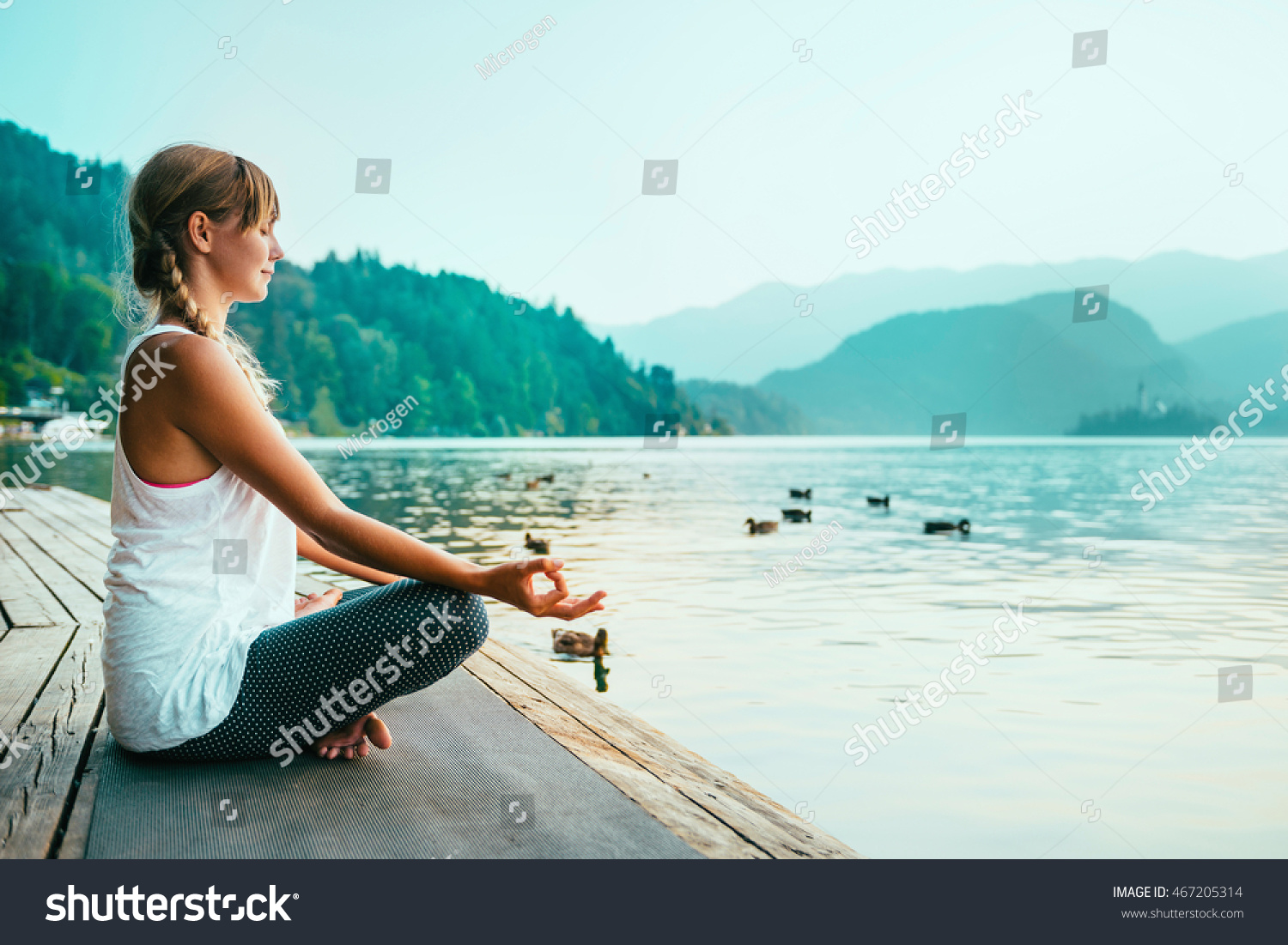 Beautiful woman in lotus position, meditating by the lake, sunset, water birds #467205314