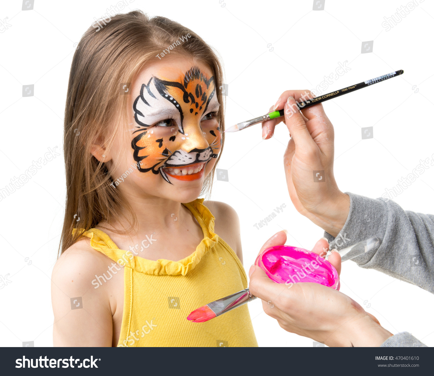 joyful little girl getting her face painted like tiger by artist #470401610
