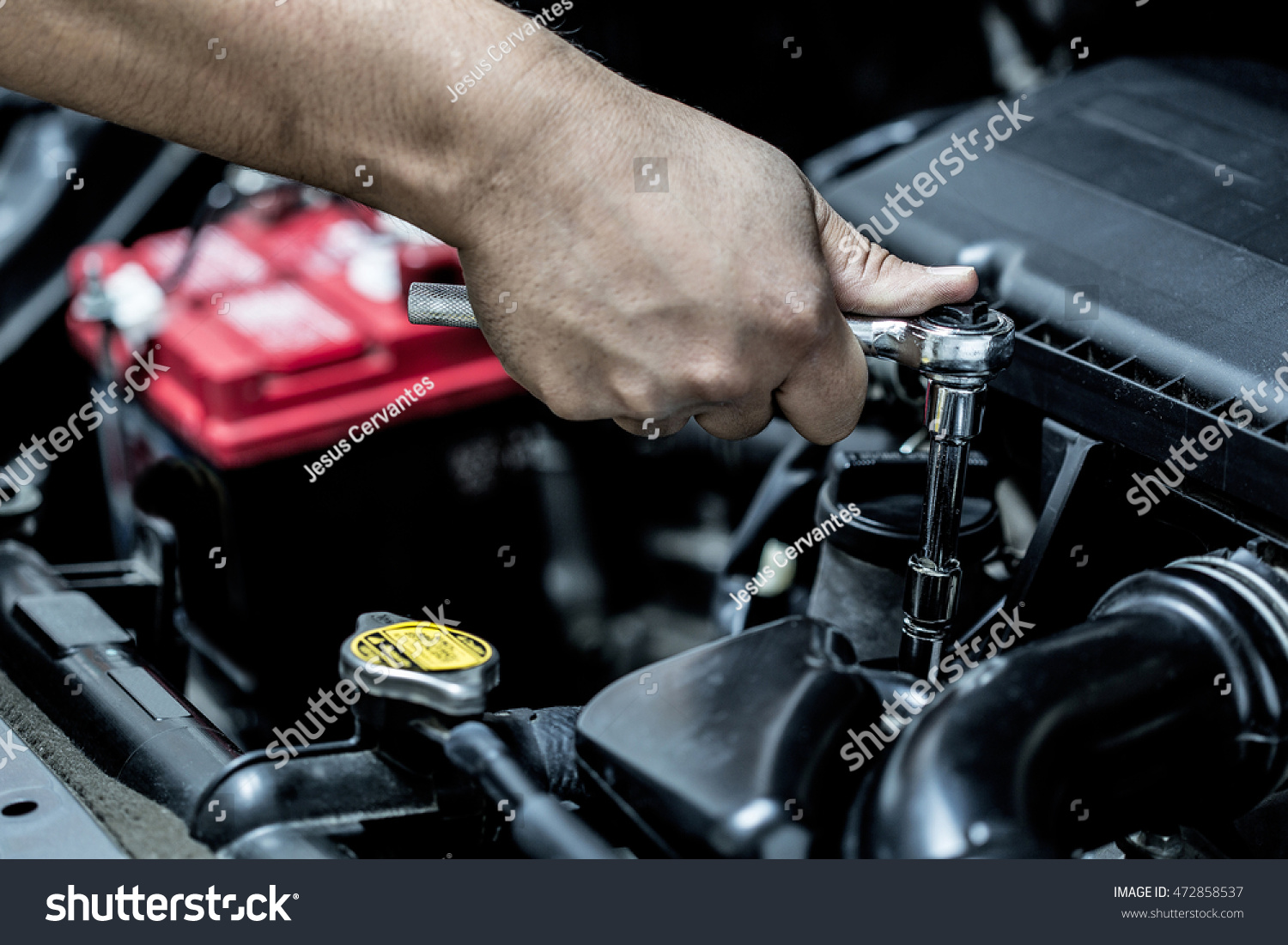 Mechanic hand checking and fixing a broken car in car service garage #472858537