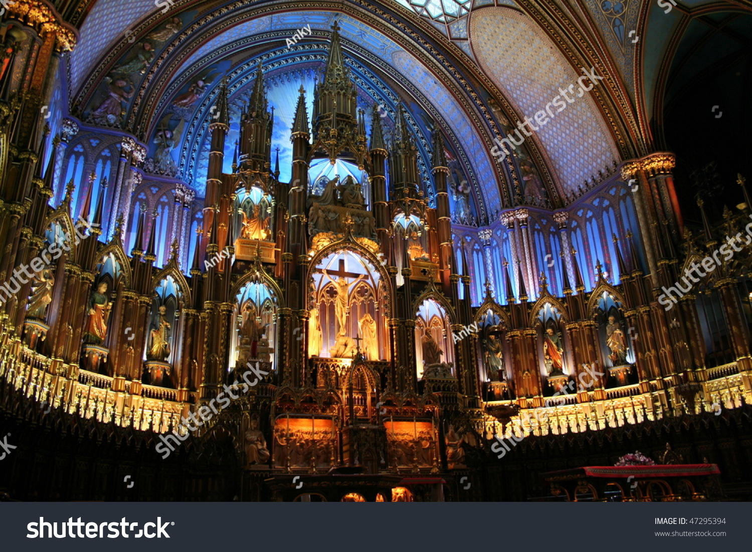 Interior of the Notre-Dame Basilica (Basilique Notre-Dame) in Montreal, Canada with deep blue ceiling with golden stars and sanctuary in polychrome of blues, azures, reds, purples, silver, and gold #47295394