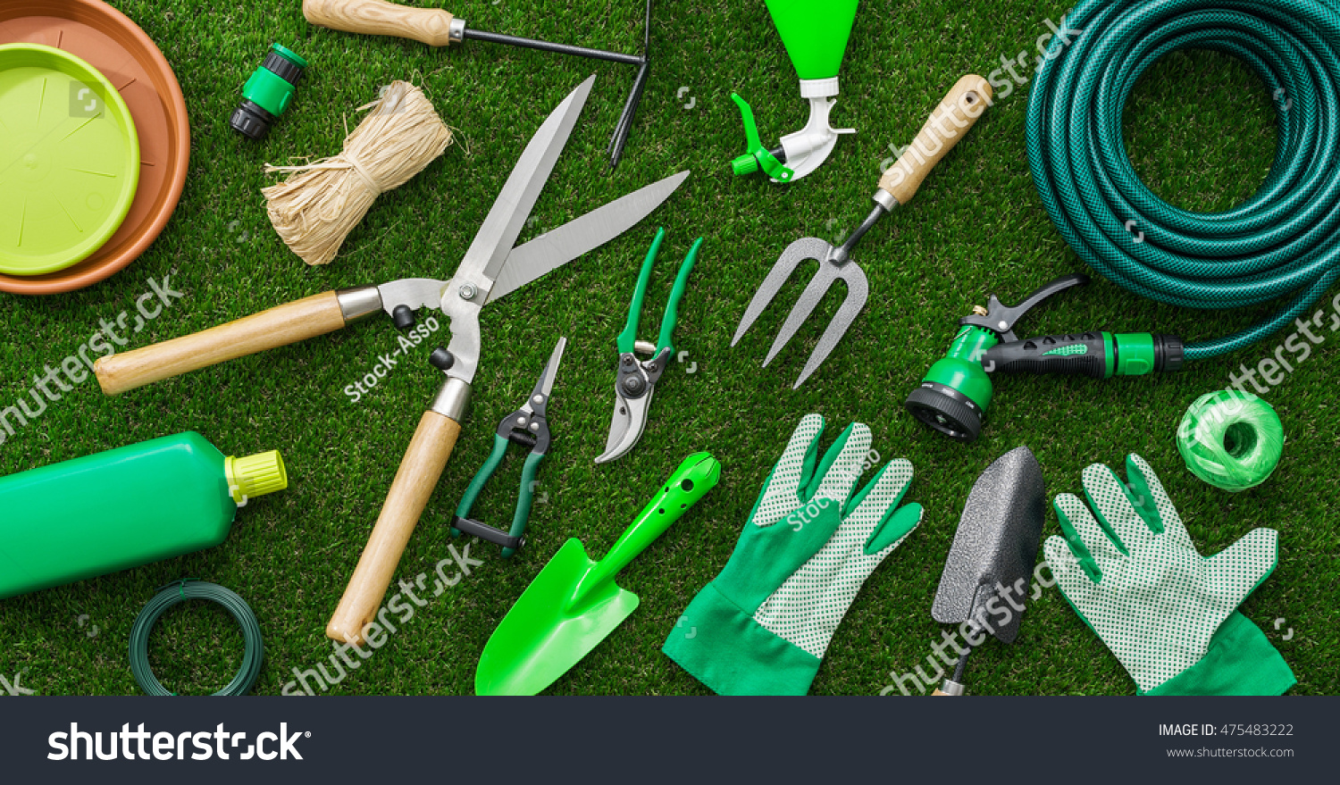 Gardening tools and utensils on a lush green meadow, top view, garden manteinance, landscaping and hobby concept #475483222