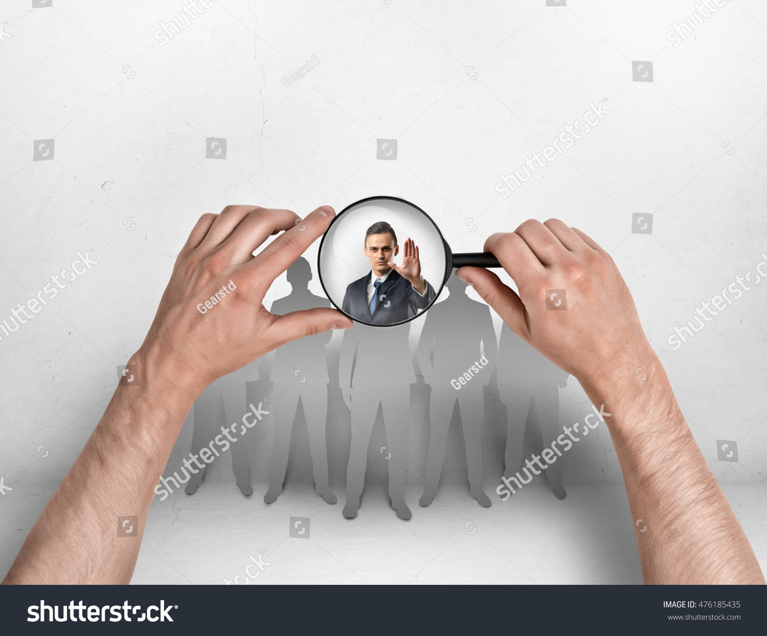 Close-up view of a man's hands focusing magnifier on a businessman with his hand raised. Body language. Stop sign. Employment issues. #476185435