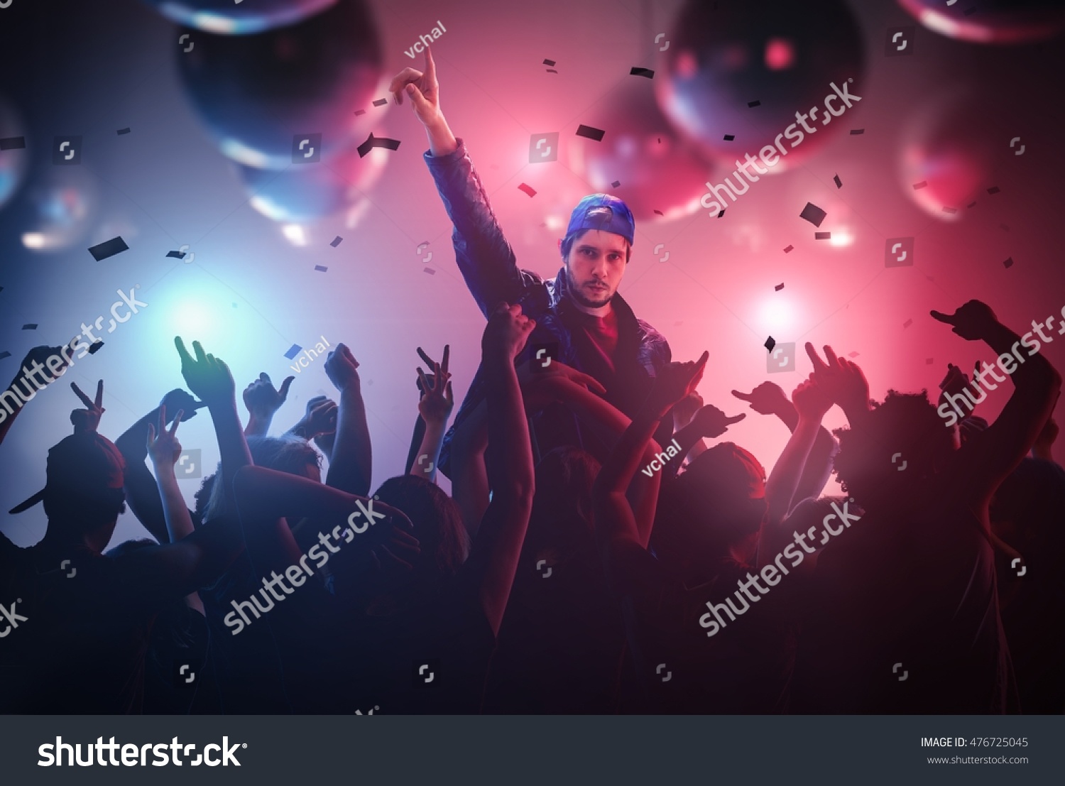 DJ or singer has hand up at disco party in club with crowd of people. #476725045