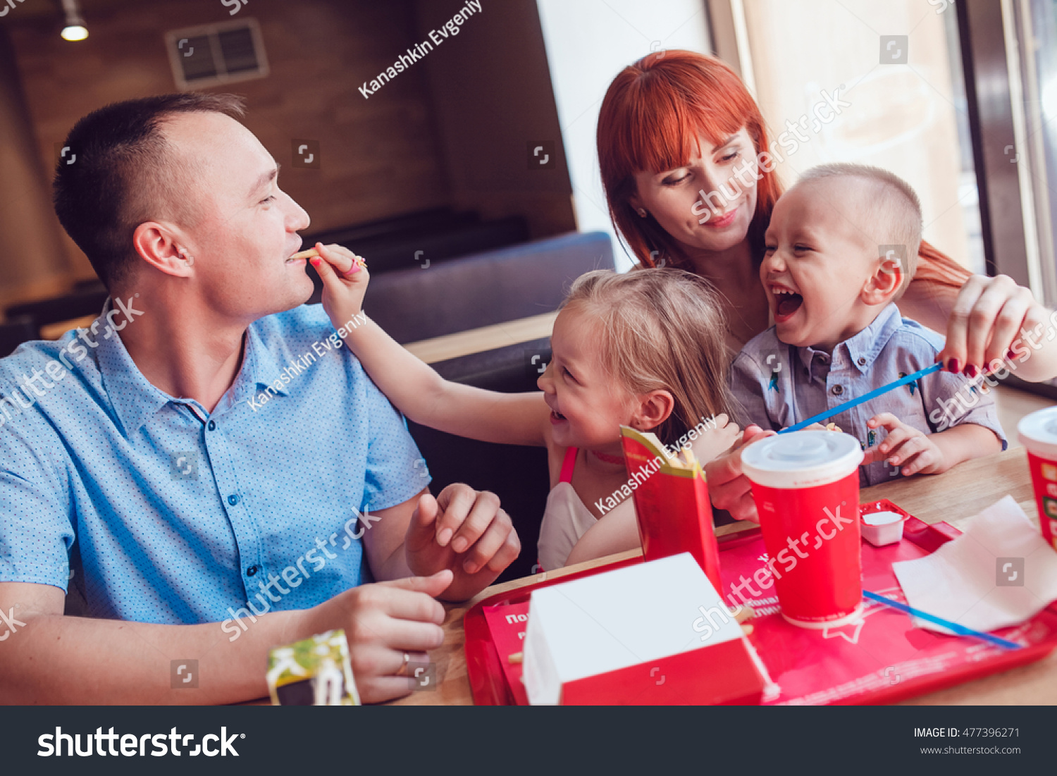 Happy family eating fast food in restaurant all together #477396271