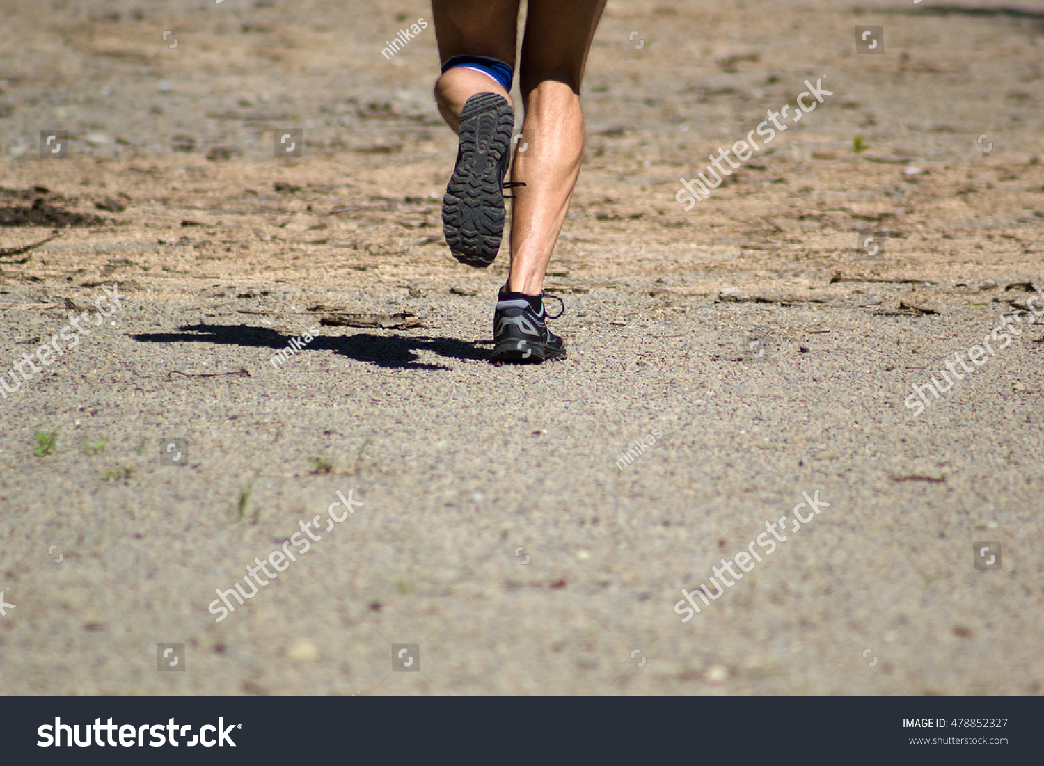 Athletic male feet running on dirt road #478852327
