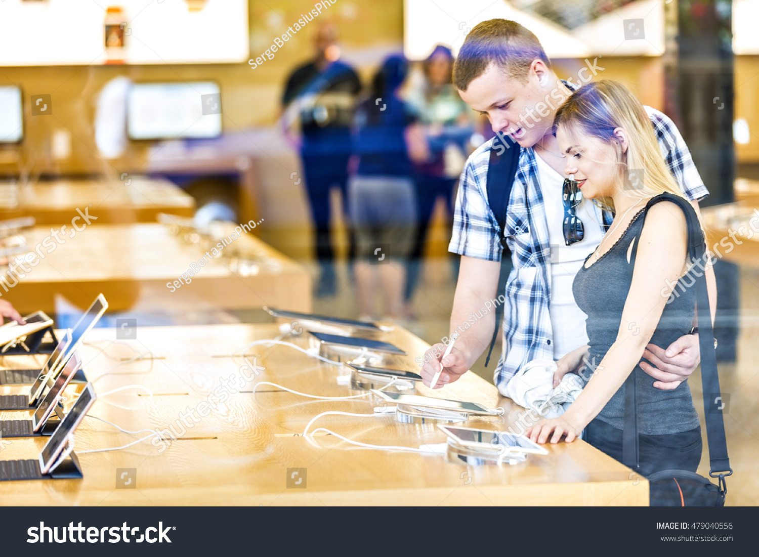 Young couple in consumer electronics retail store browsing at displayed latest tablets, choosing new device. #479040556