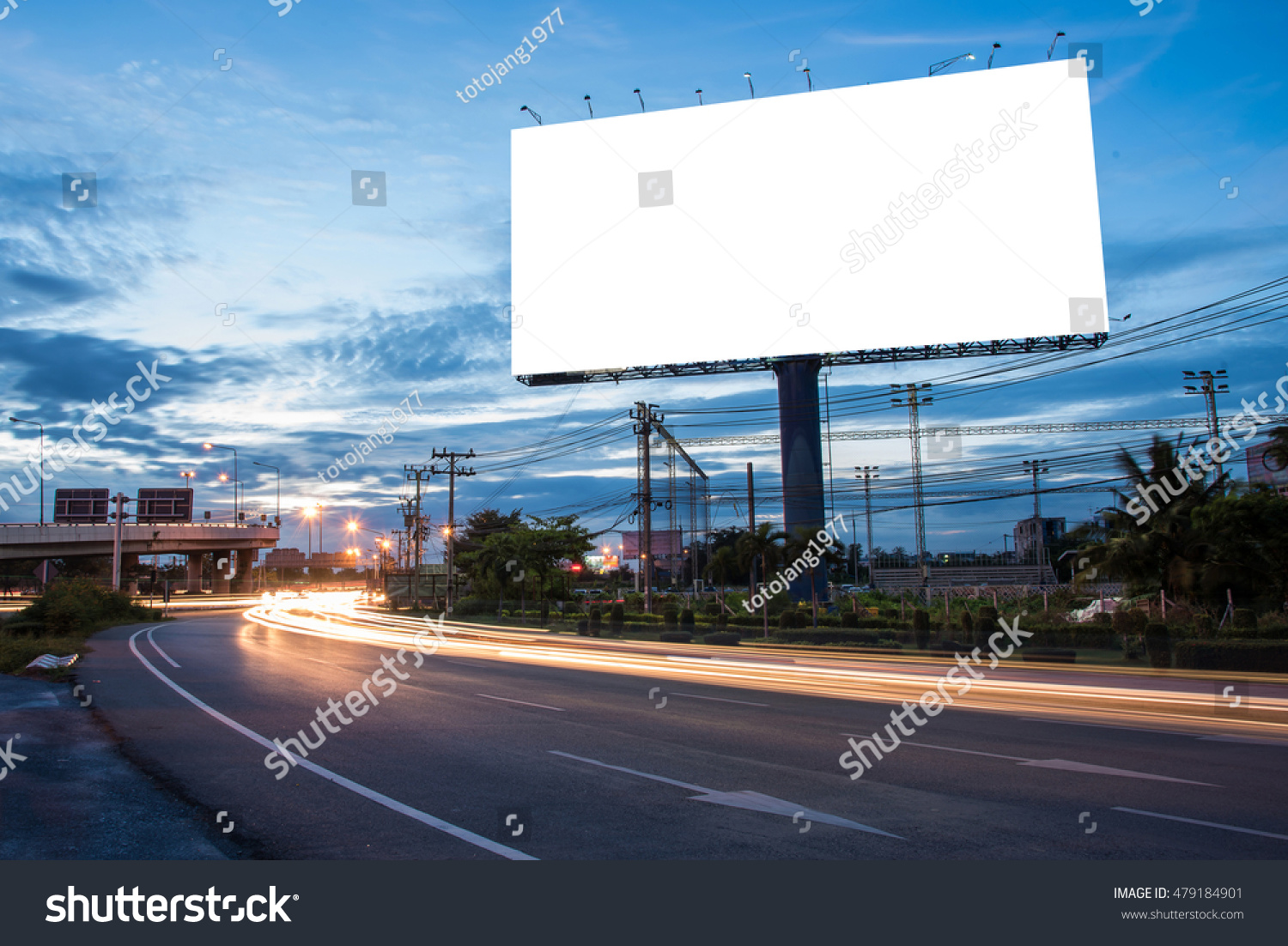 Blank billboard for advertisement at twilight time with light trails on the road at dusk, business advertising concept. #479184901