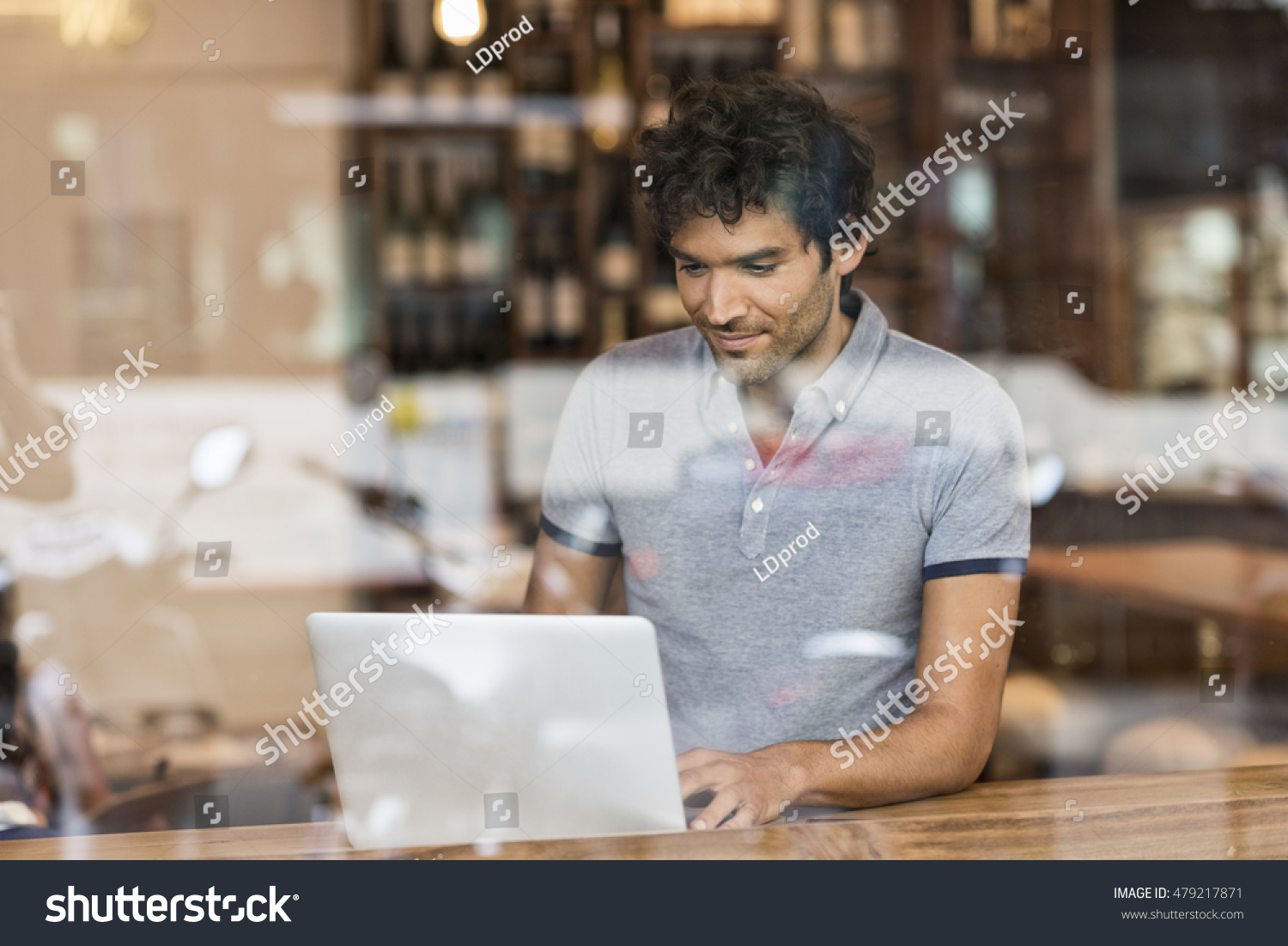Young man sitting in coffee bar. Working on laptop. Reflection through the glass #479217871