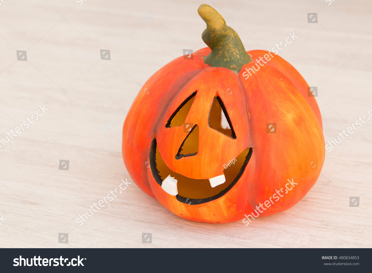 Orange pumpkin lantern with a spooky face smiling on a wooden grey background #480834853