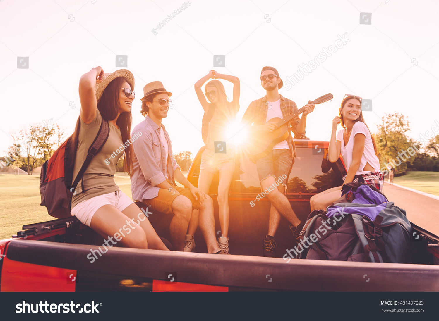 Enjoying the best road trip ever. Group of young cheerful people enjoying their road trip while sitting in pick-up truck together  #481497223