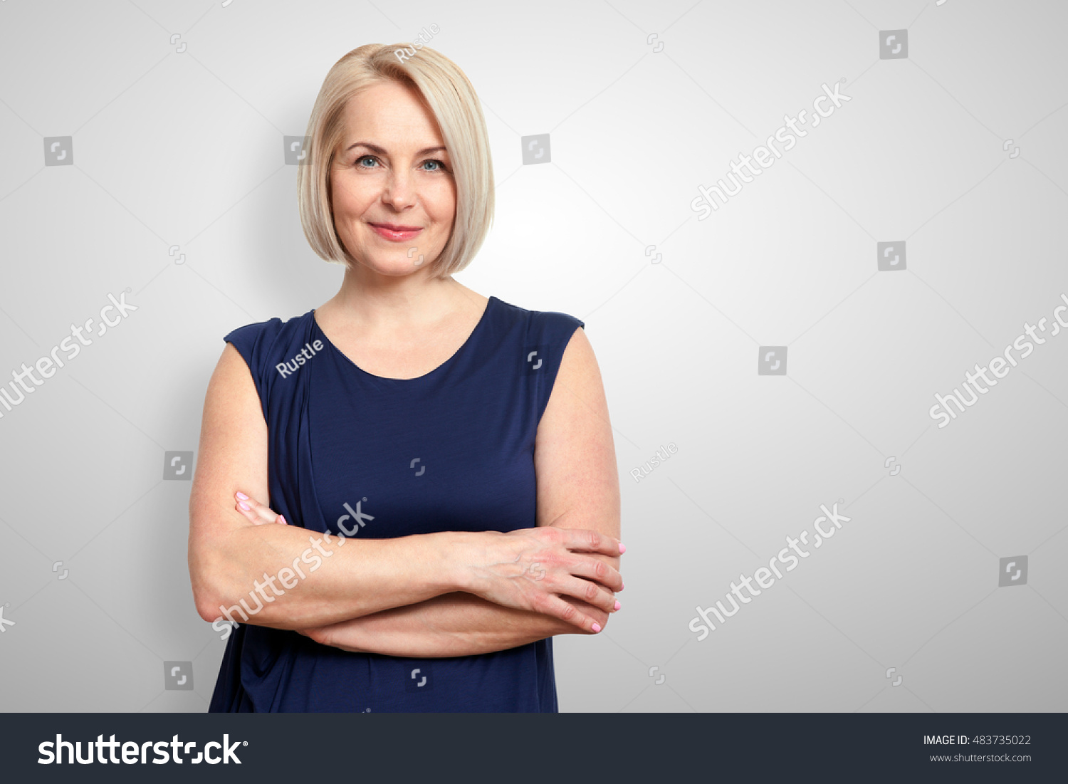 Attractive middle aged woman with folded arms on grey background #483735022