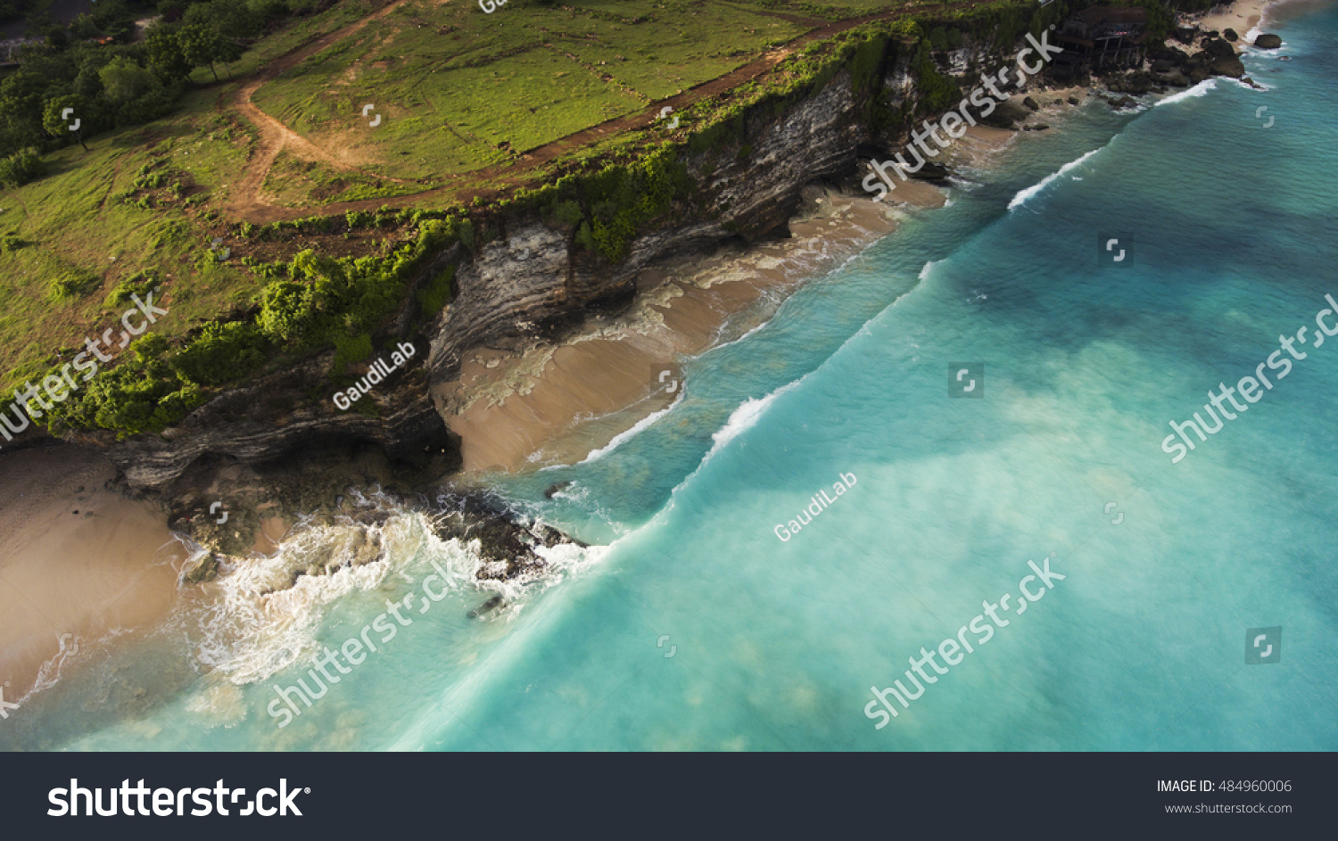Aerial photo from flying drone of an amazing nature scenery with rock cliff on sandy coastline. Beautiful sea water with waves for surfing in summer season in Bali. Beauty Indian ocean landscape #484960006