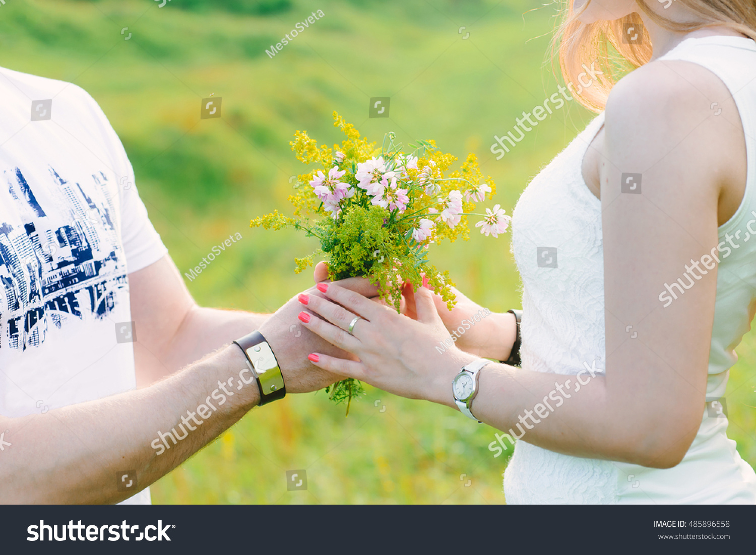 A photo of a man presenting a cute wildflowers bouquet to his girl, romantic, green background #485896558