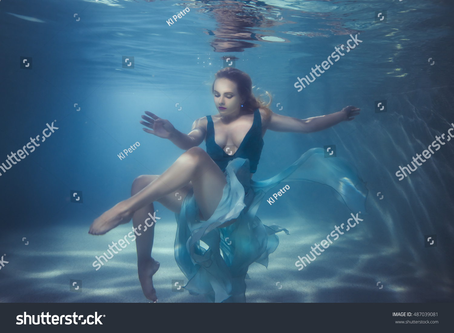 Woman in a dress dives underwater, she dances on the bottom. #487039081