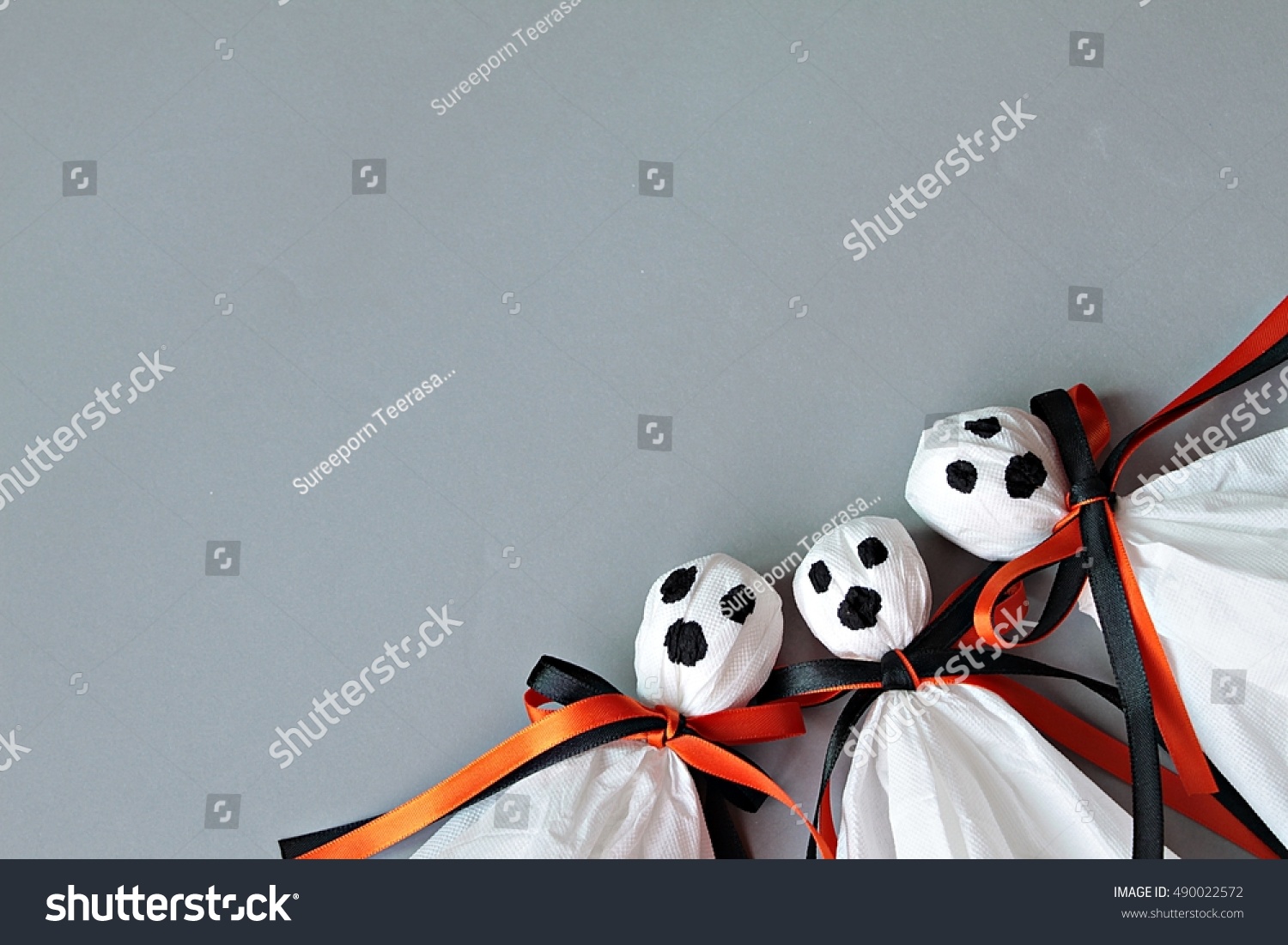 Halloween concept background : Three halloween ghosts DIY made from white tissue paper, black and orange ribbon on gray background
 #490022572