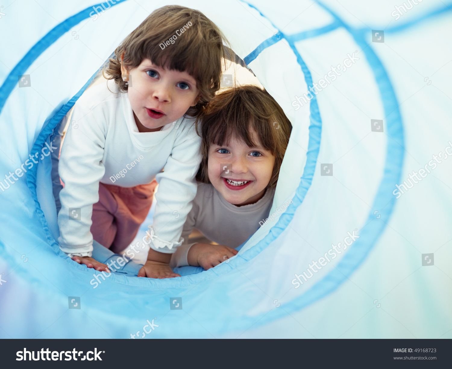 two 2-3 years old girls peeking from blue toy tunnel. Horizontal shape, Copy space #49168723