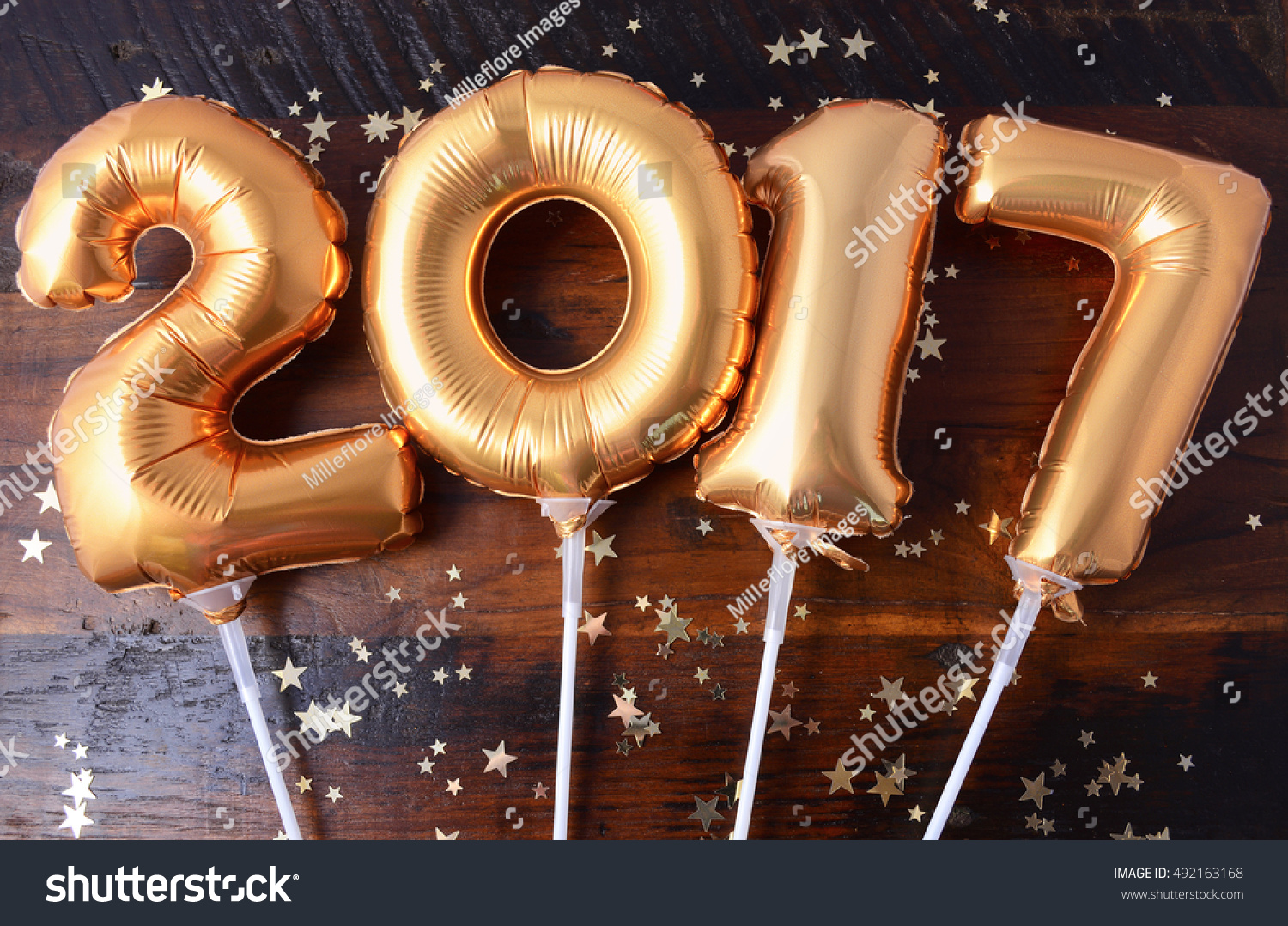 Happy 2017 gold New Year Balloons with glitter stars on dark wood table background.  #492163168