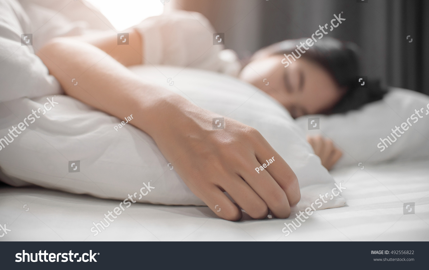 Cute girl on a soft white bed. She sleeping and relaxing. #492556822