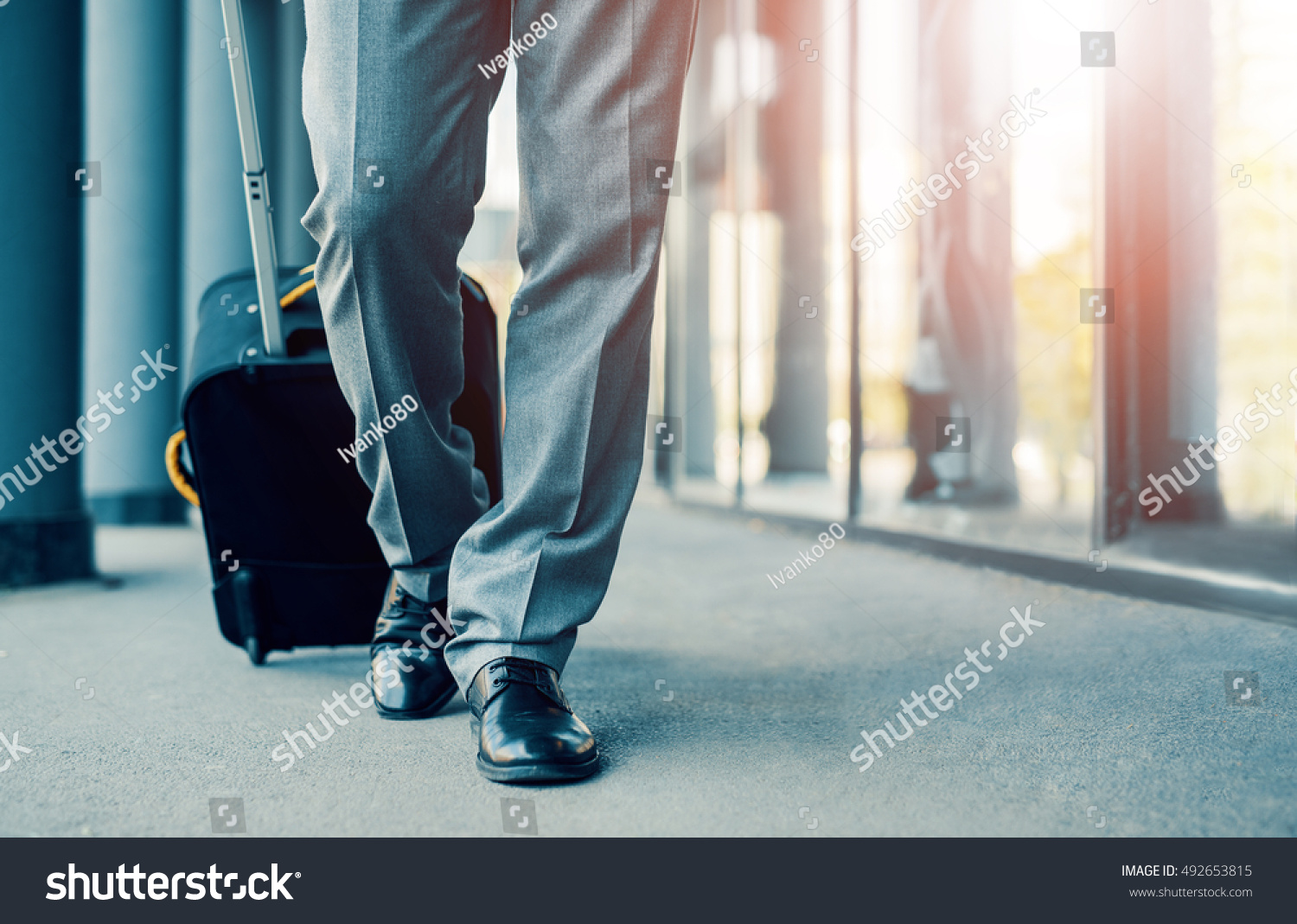 Close up of businessman carrying suitcase while walking through a passenger boarding bridge. #492653815