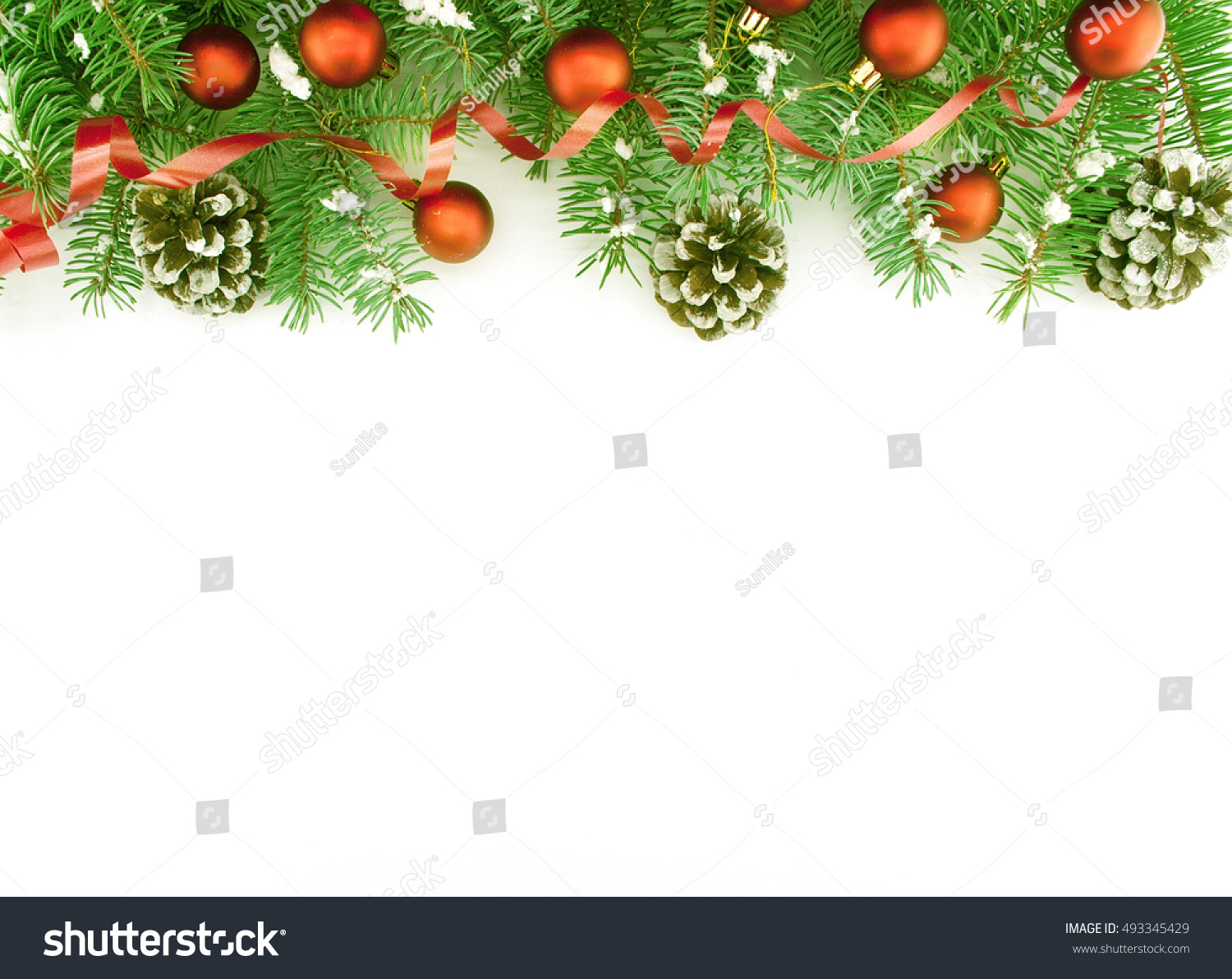 Frame of Christmas tree branches with Christmas decoration: red baubles, ribbon, pinecone and snowflakes isolated on white. Holiday background. Top view #493345429
