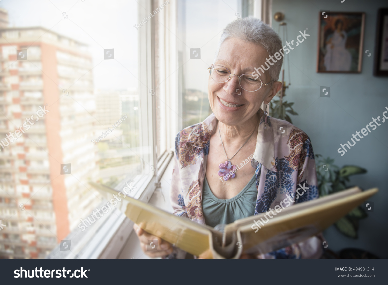 Senior lady looking at old photographs in an album, remembering her past #494981314