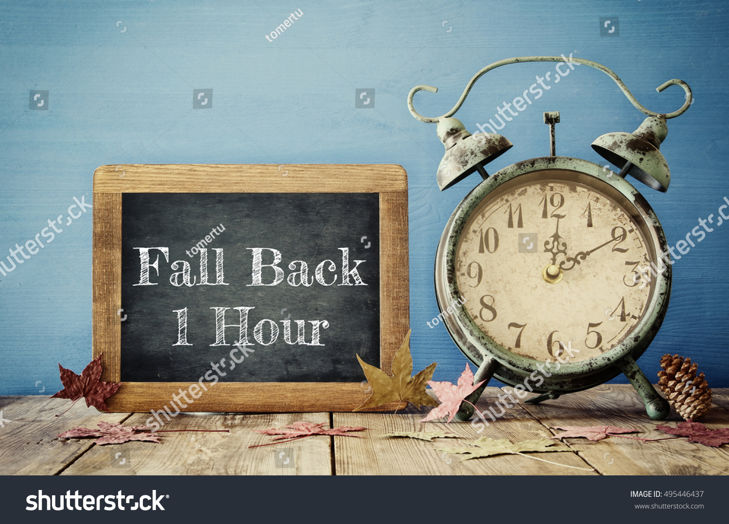 Image of autumn Time Change. Fall back concept. Dry leaves and vintage alarm Clock on  rustic wooden table #495446437