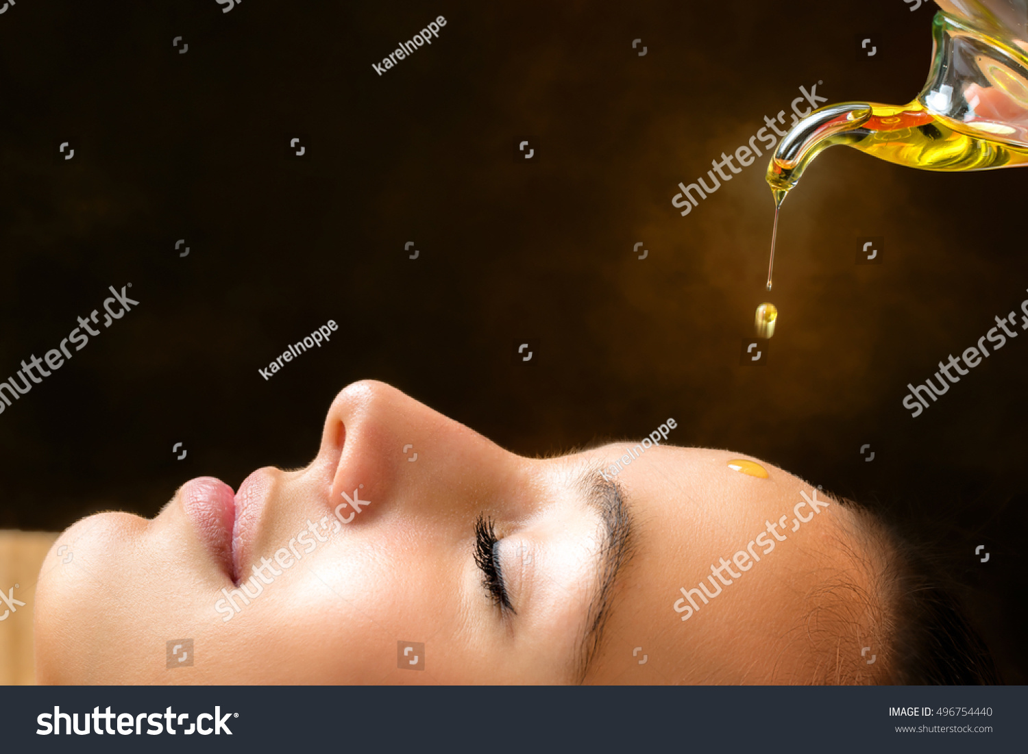 Macro close up portrait of young woman at ayurvedic massage session with aromatic oil dripping on face. #496754440