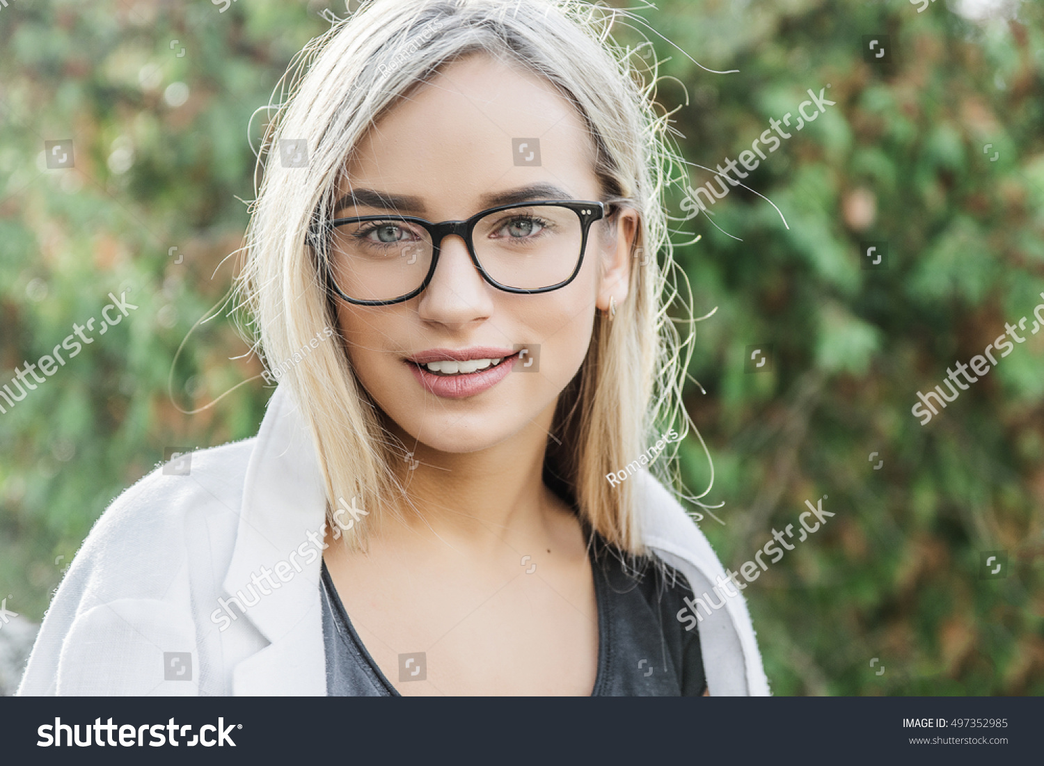 portrait of a young woman, blonde, glasses, outdoors in the park #497352985