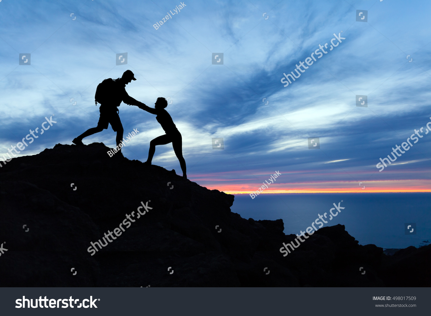 Teamwork couple hiking, help each other, trust assistance and silhouette in mountains, sunset over ocean. Team of climbers man and woman helping hand on mountain top, inspirational climbing team. #498017509