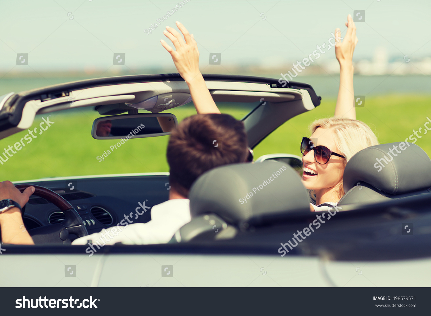 transport, road trip, leisure, couple and people concept - happy man and woman driving in cabriolet car outdoors #498579571