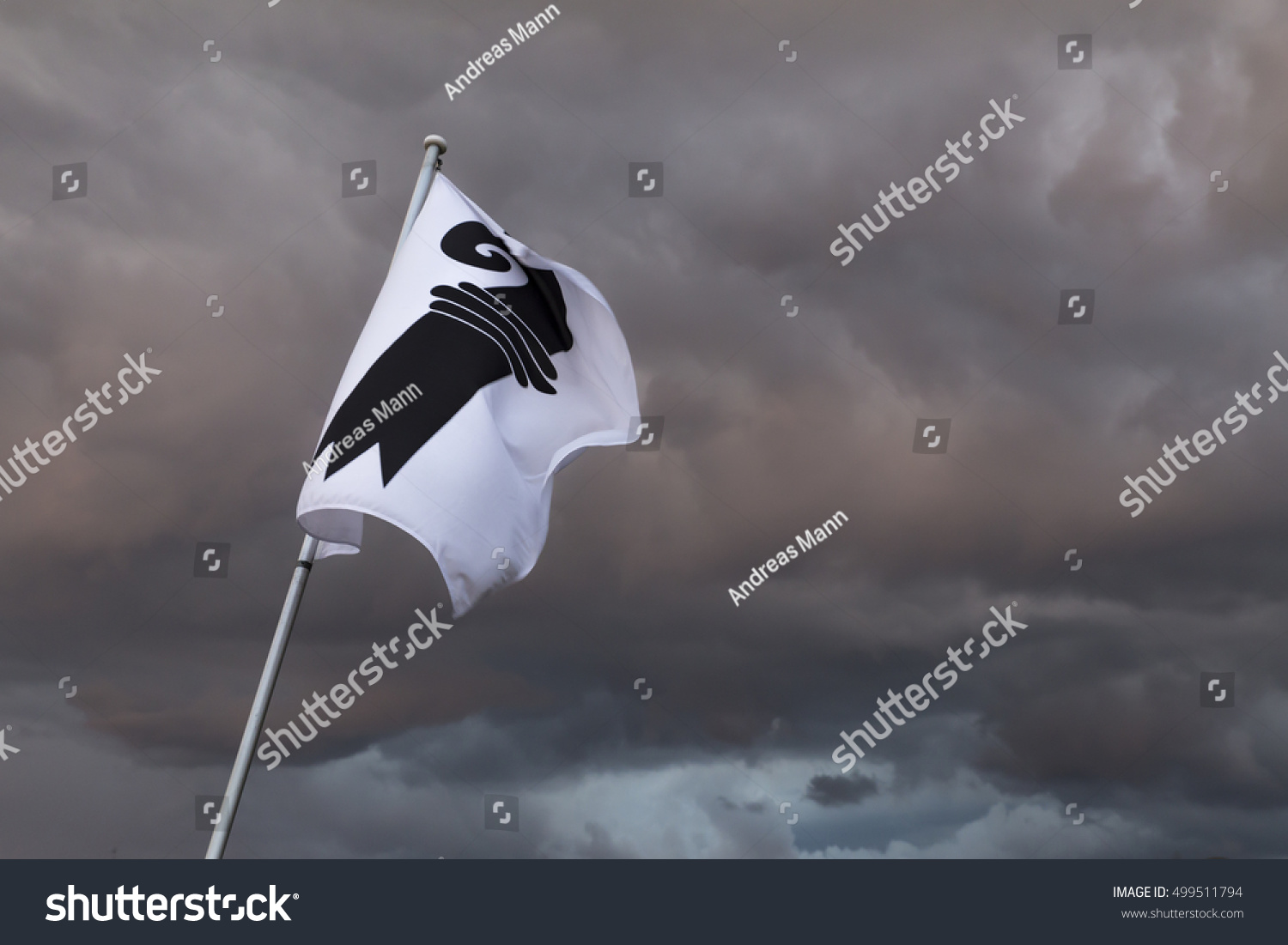 A single flag of Basel in Switzerland in front of a gloomy sky. Dark storm clouds loom in the background #499511794