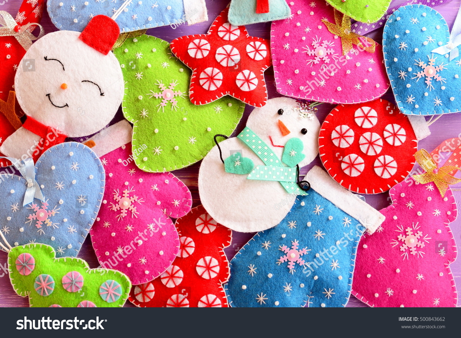 Kids Christmas background. Cute felt ornaments for Christmas. Felt Christmas trees, snowmen, hearts, stars, mittens toys. Mixed hanging Christmas decorations diy red green white blue pink. Top view  #500843662
