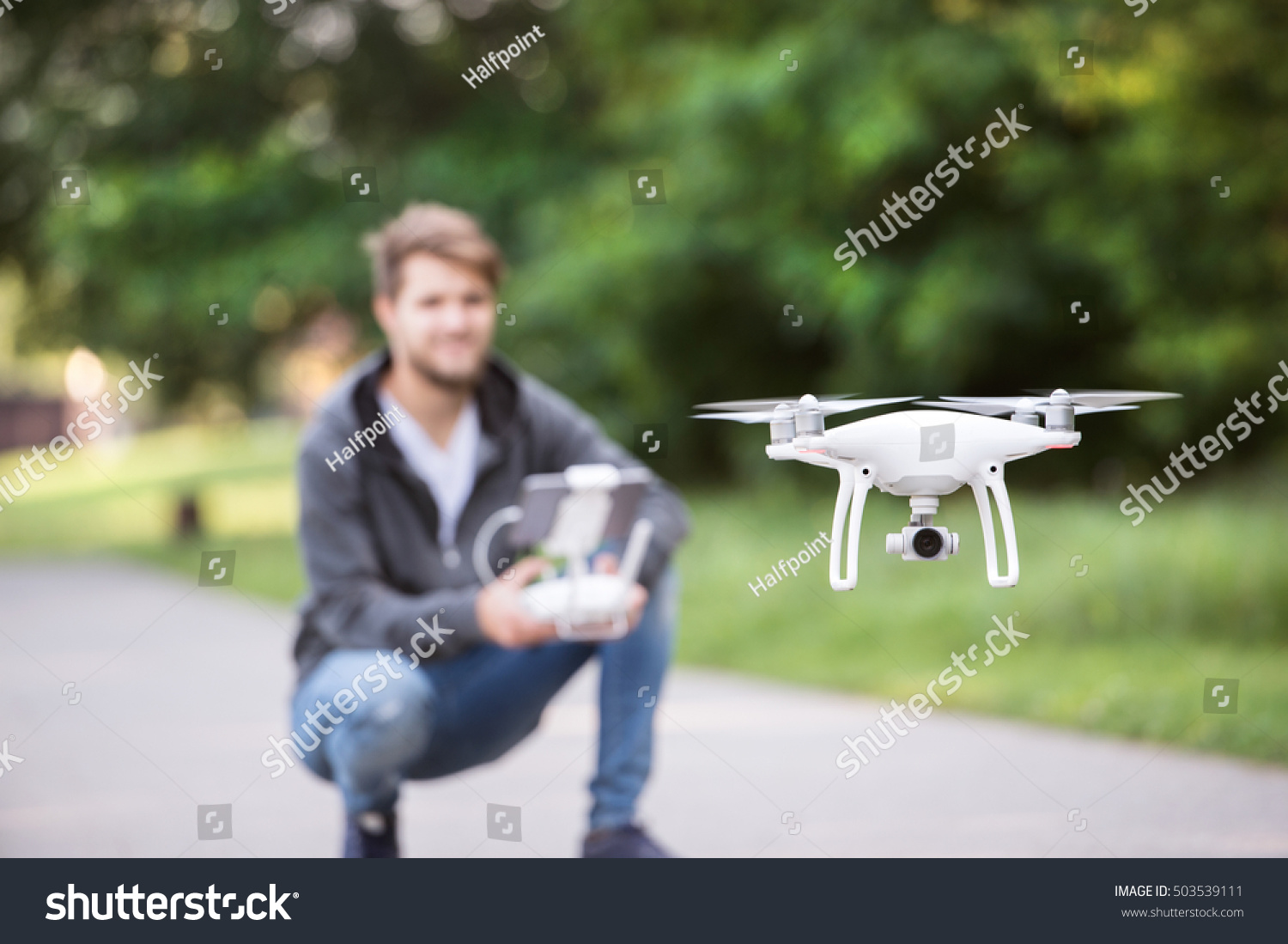 Young hipster man with flying drone. Sunny green nature. #503539111