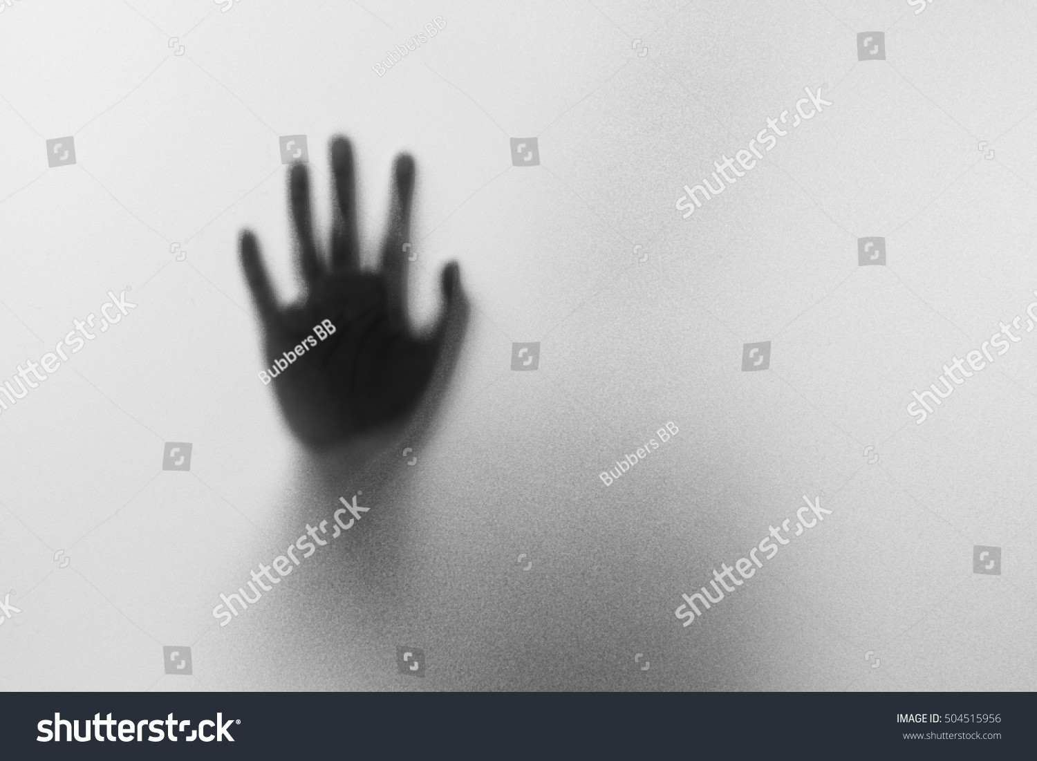 Shadow hands of the Man behind frosted glass.Blurry hand abstraction.Halloween background.Black and white picture #504515956