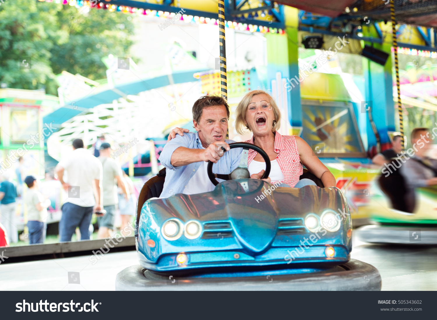 Senior couple in the bumper car at the fun fair #505343602