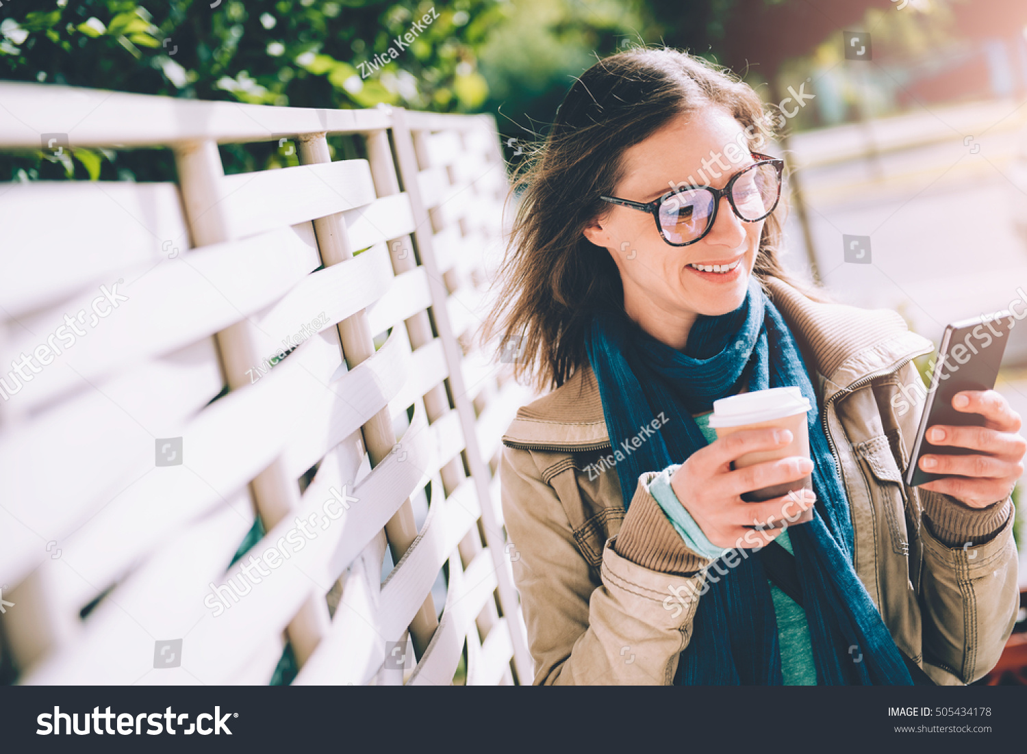 Woman holding takeaway coffee and using smart phone outdoor #505434178