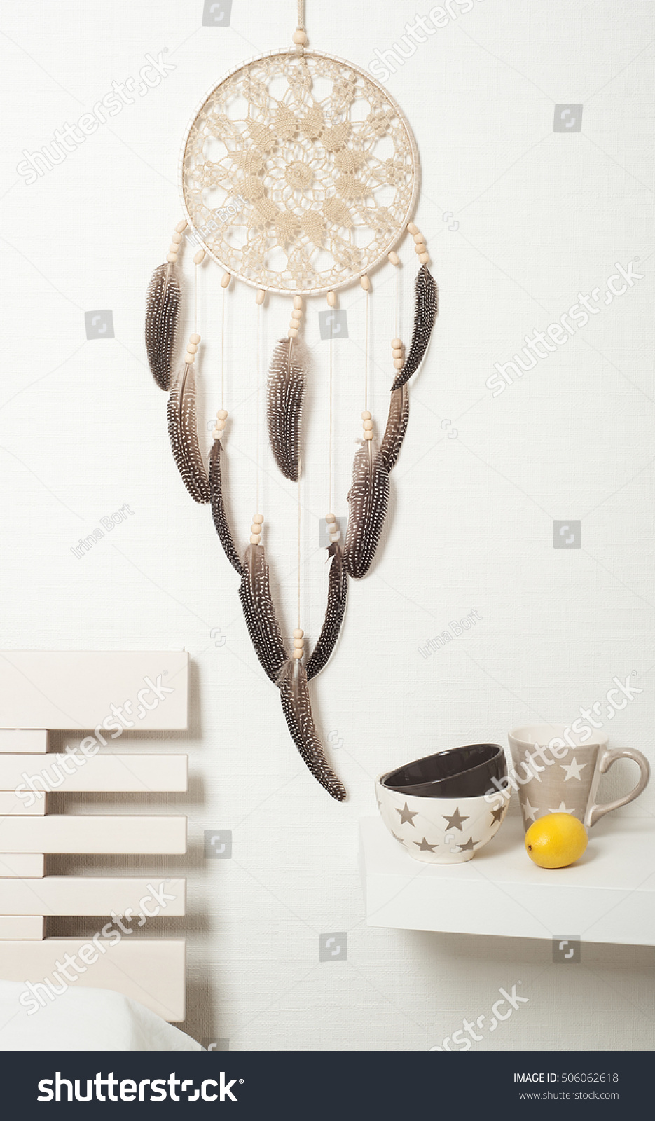 Beige brown dream catcher with feathers on white wall. Copyspace for text #506062618