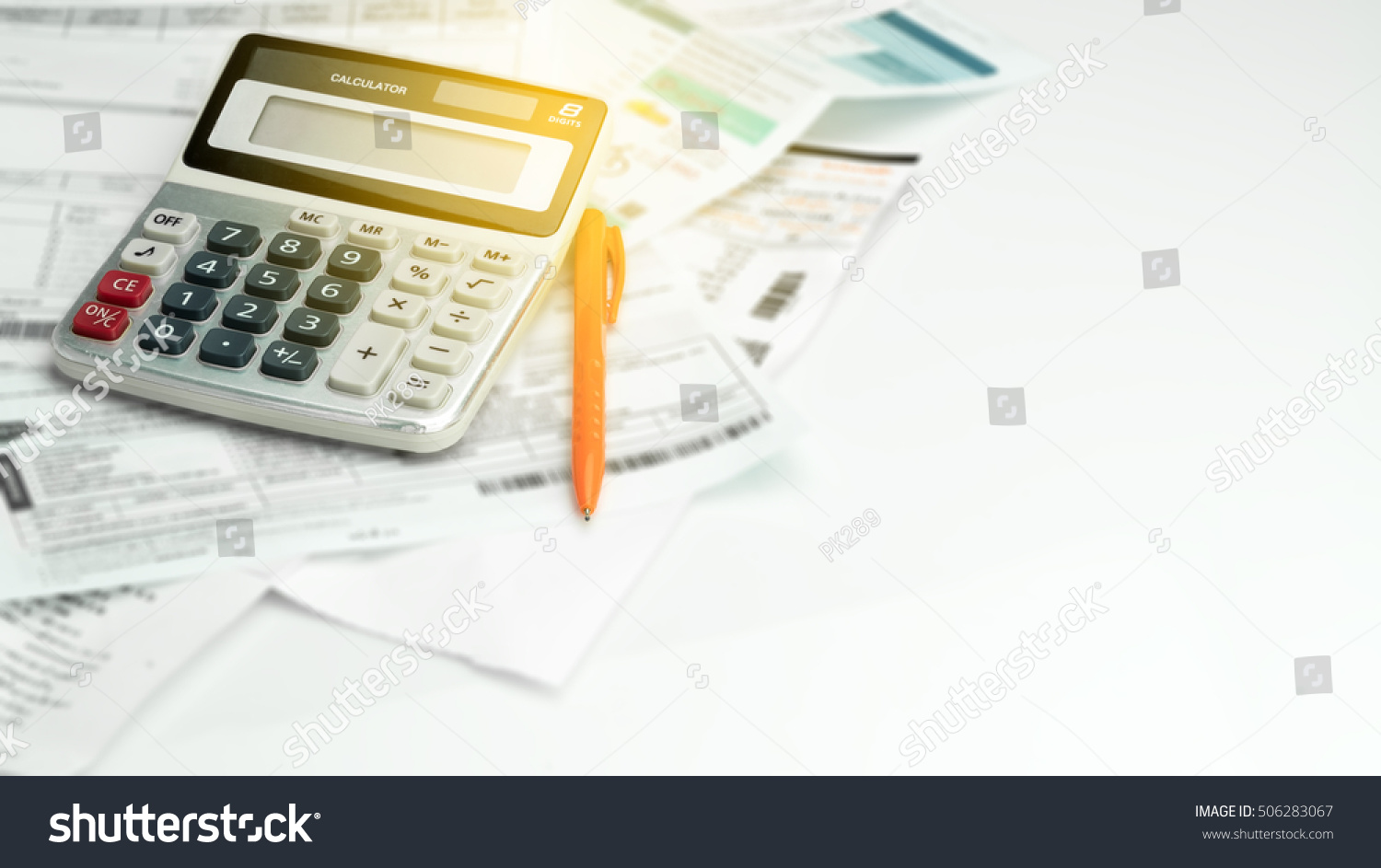 A calculator , ball pen and household bills , adding light  #506283067