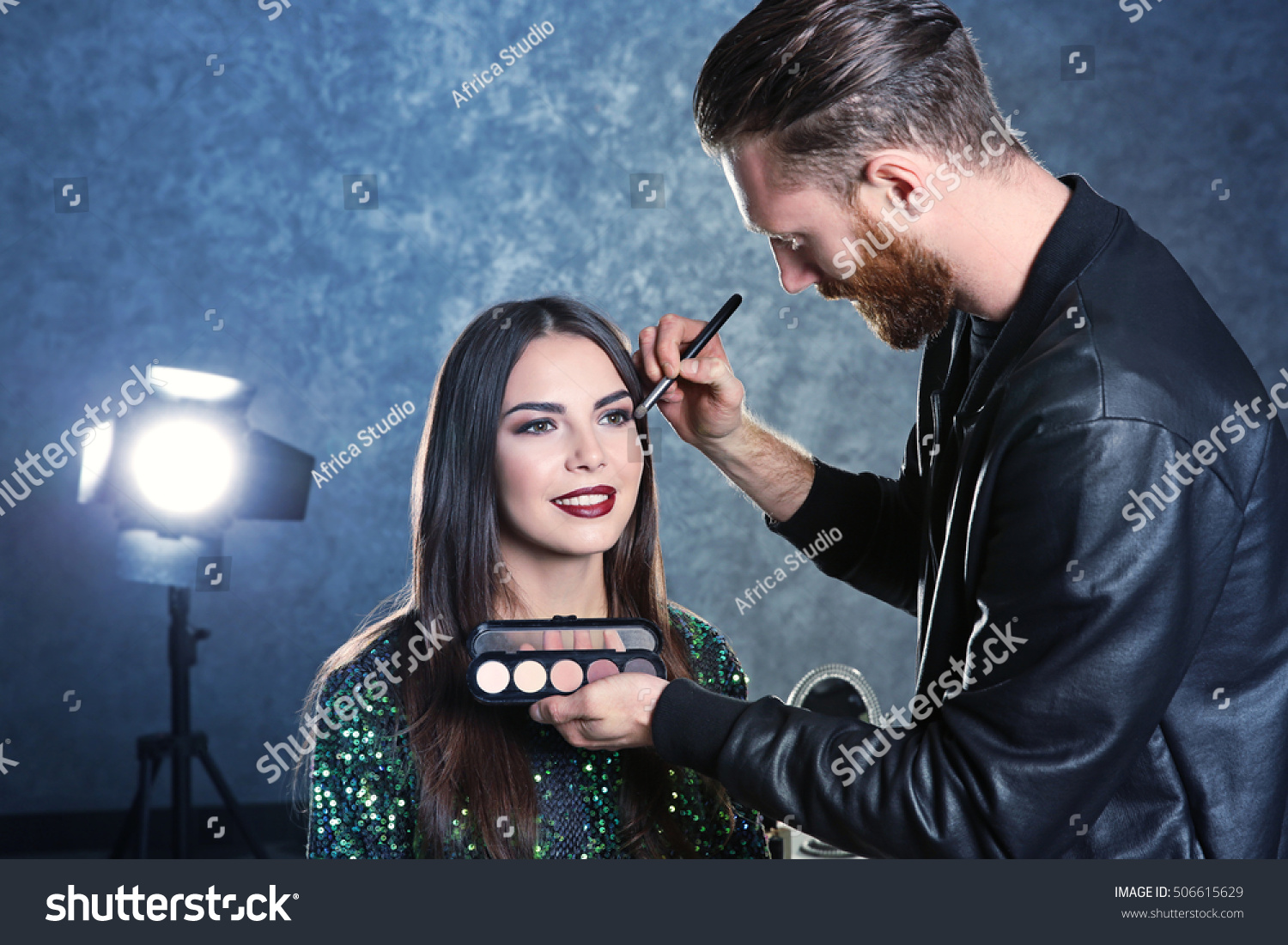Professional makeup artist working with beautiful young woman #506615629