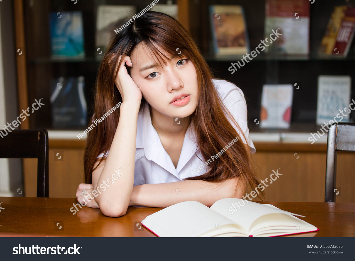 Portrait of thai adult student university uniform beautiful girl reading red book #506733685