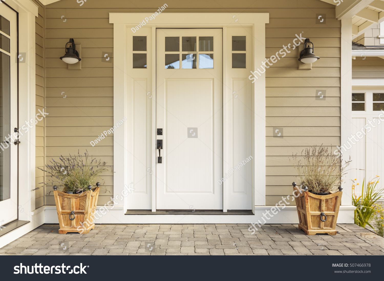 White front door with small square decorative windows and flower pots #507466978