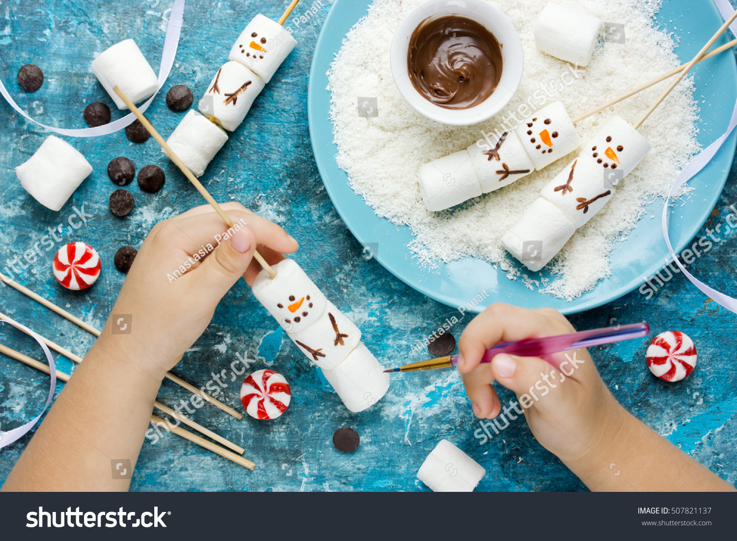 Child making snowman marshmallow pops, kitchen composition for winter holiday. Funny food art idea for Christmas dessert treat top view #507821137