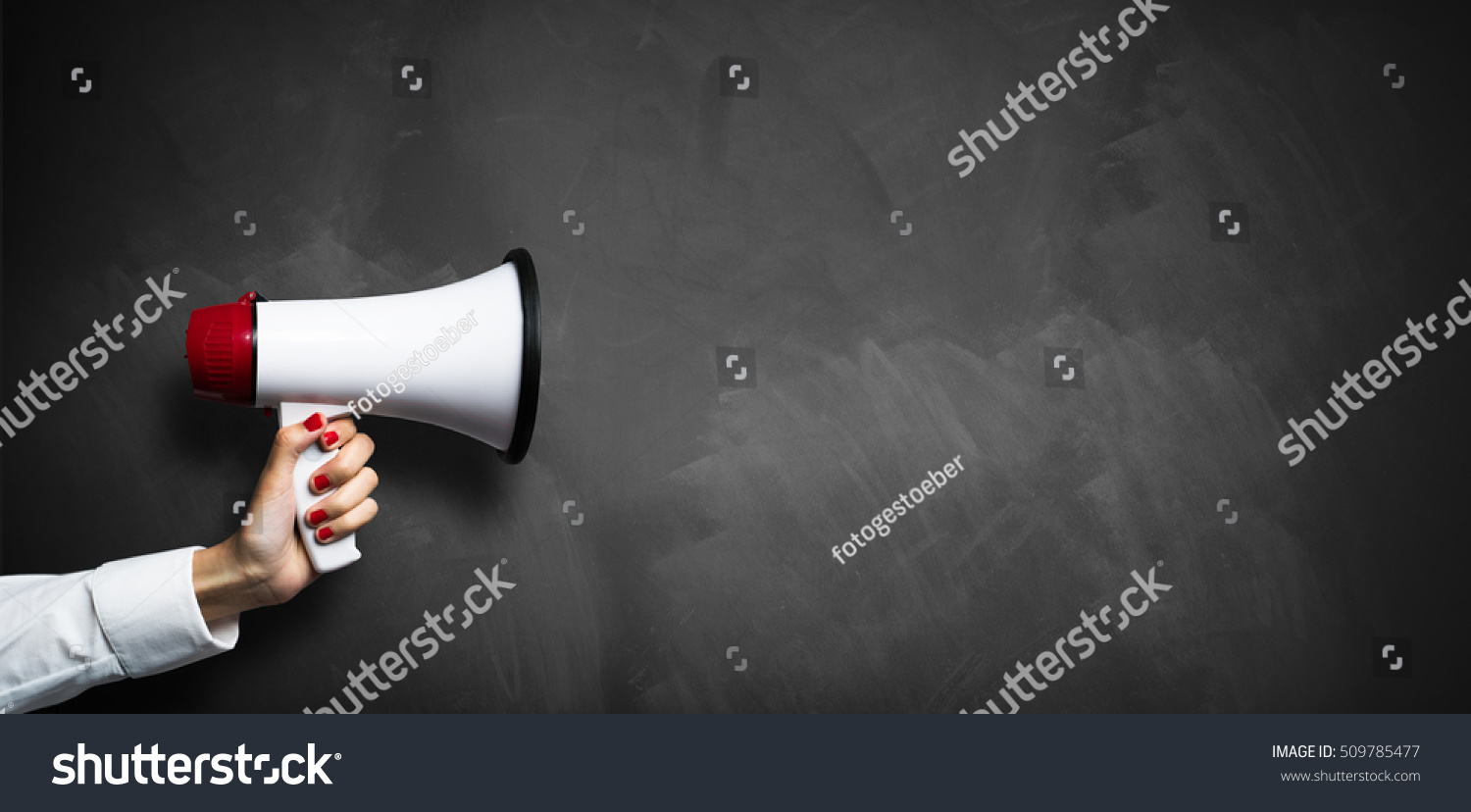 hand with a megaphone in front of an empty blackboard #509785477