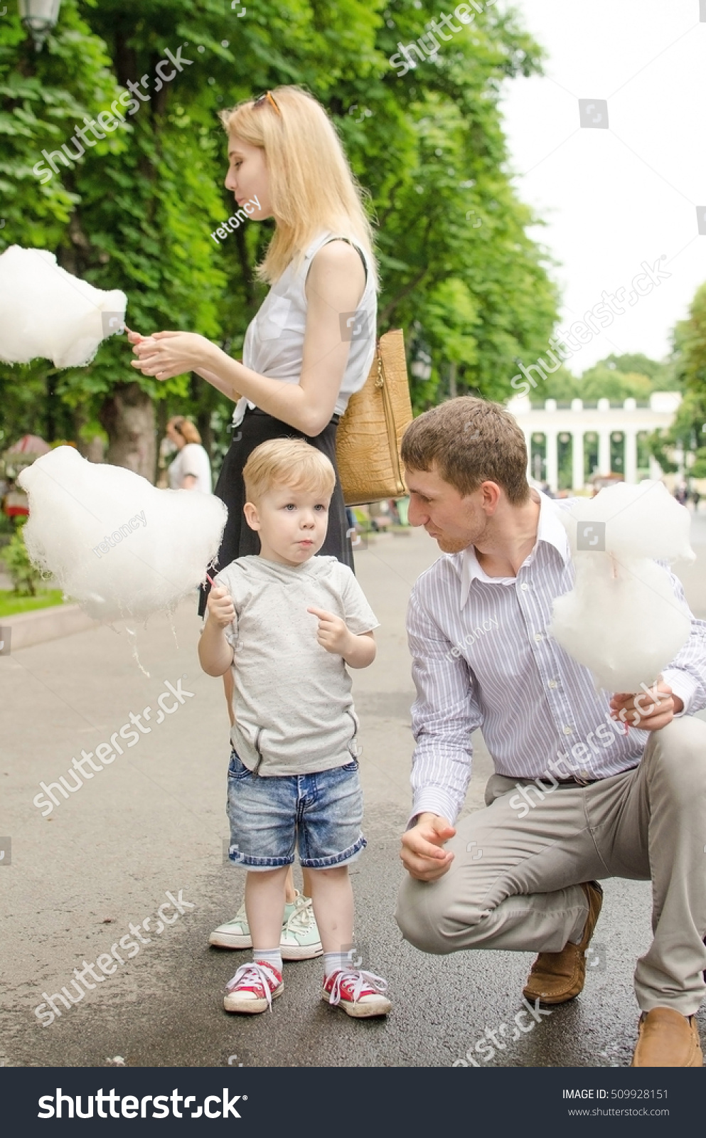Young family is eating cotton candy in the park #509928151