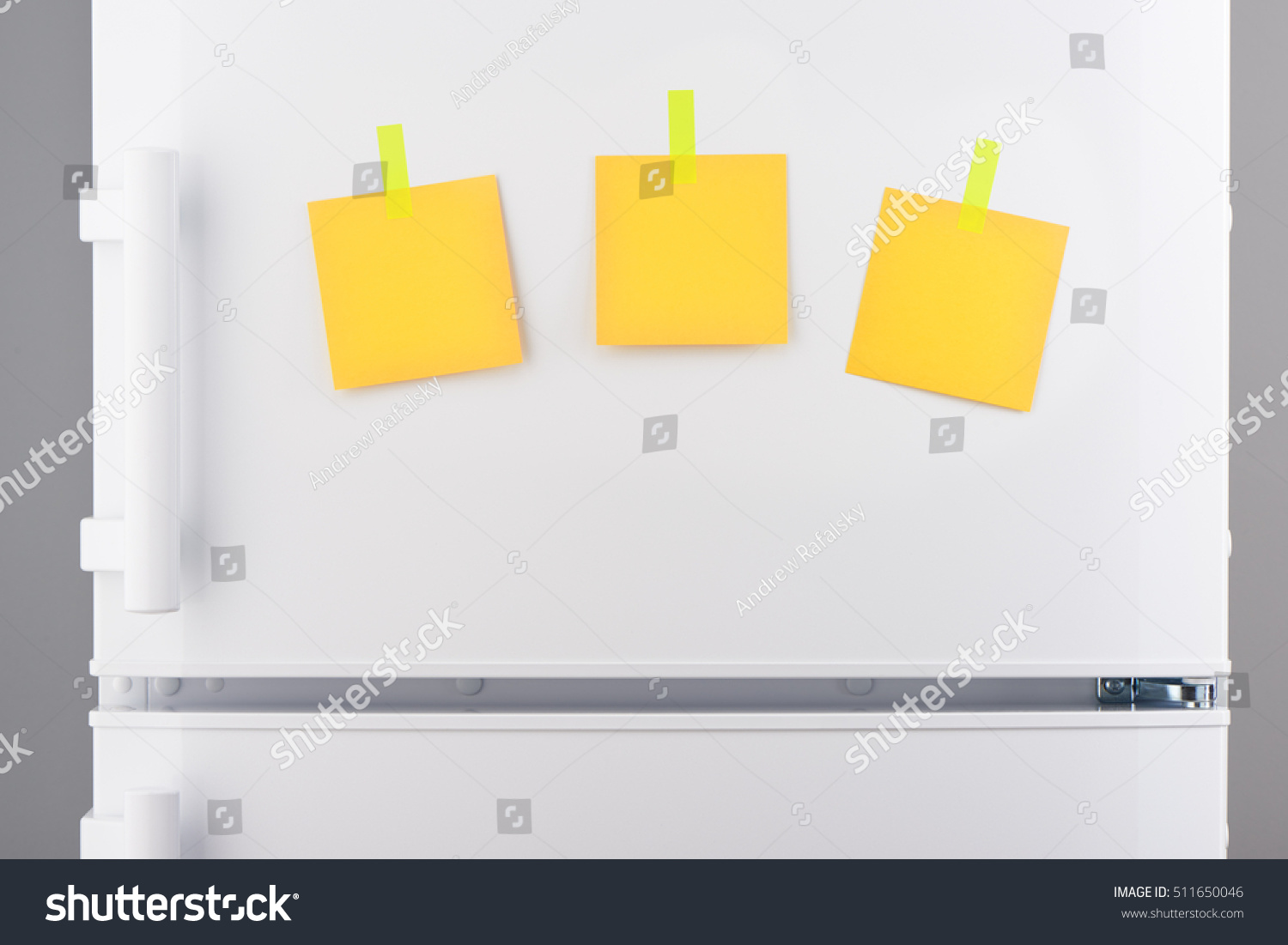 Three blank yellow paper notes attached with yellow stickers on white refrigerator door #511650046