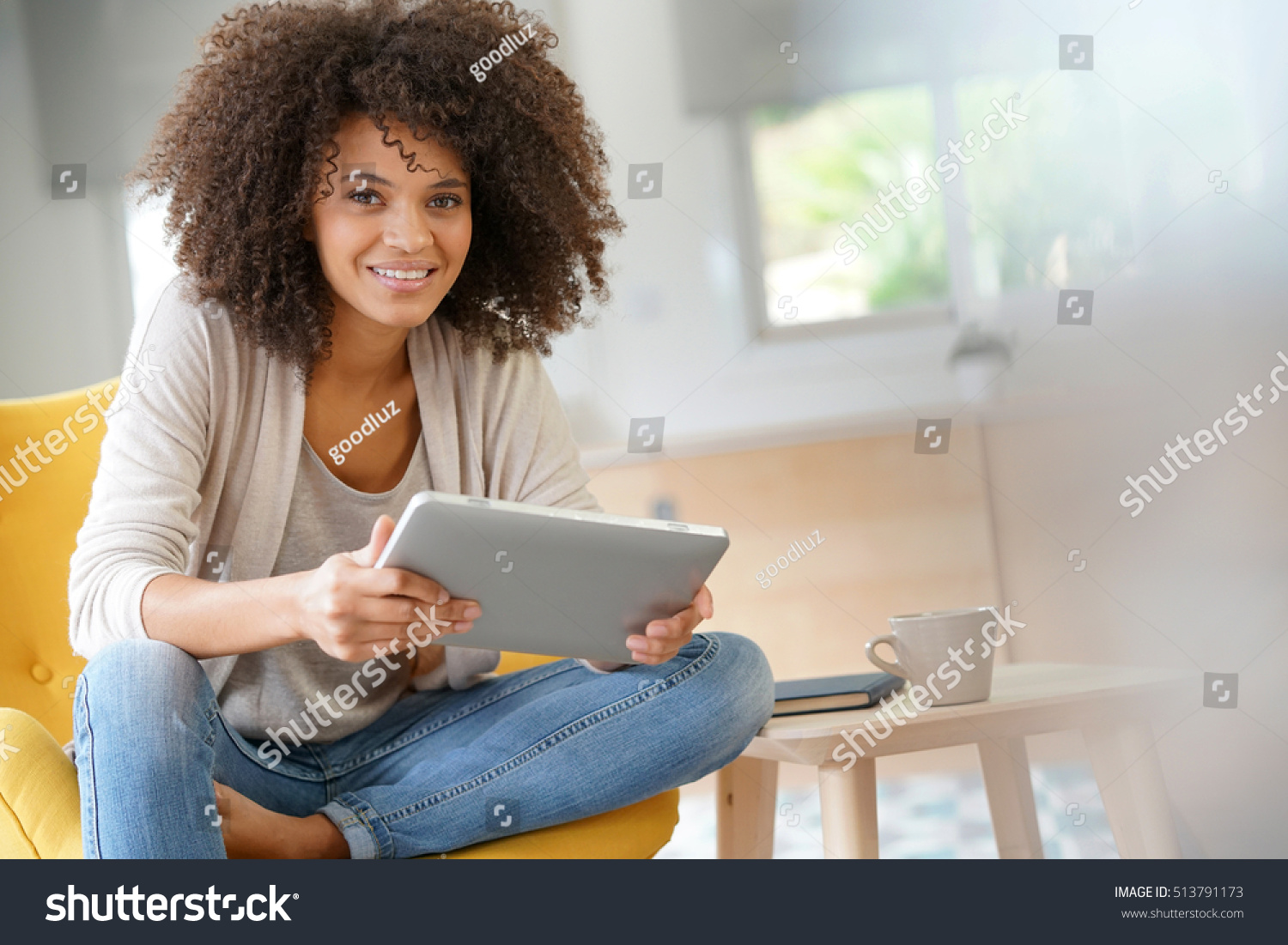 Mixed-race woman websurfing on digital tablet at home #513791173