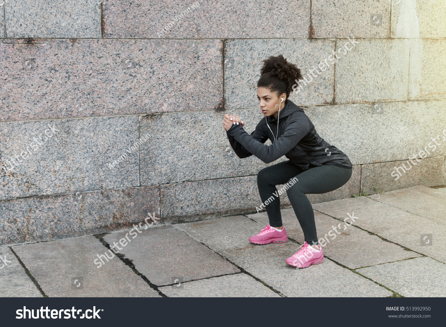 Sporty woman doing warm up squat, stretching near a wall #513992950