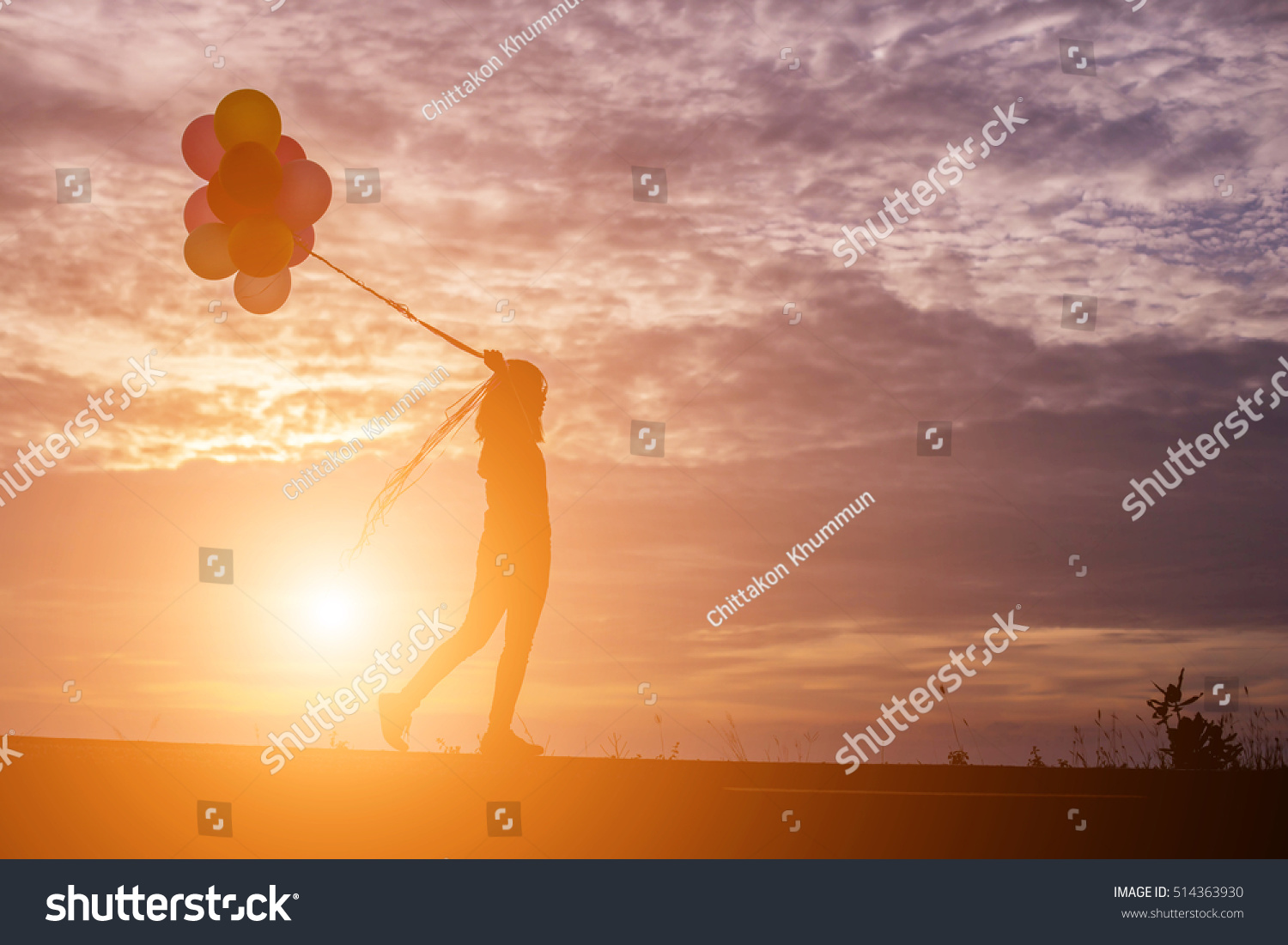  silhouette of young woman holding colorful of balloons with sunset #514363930